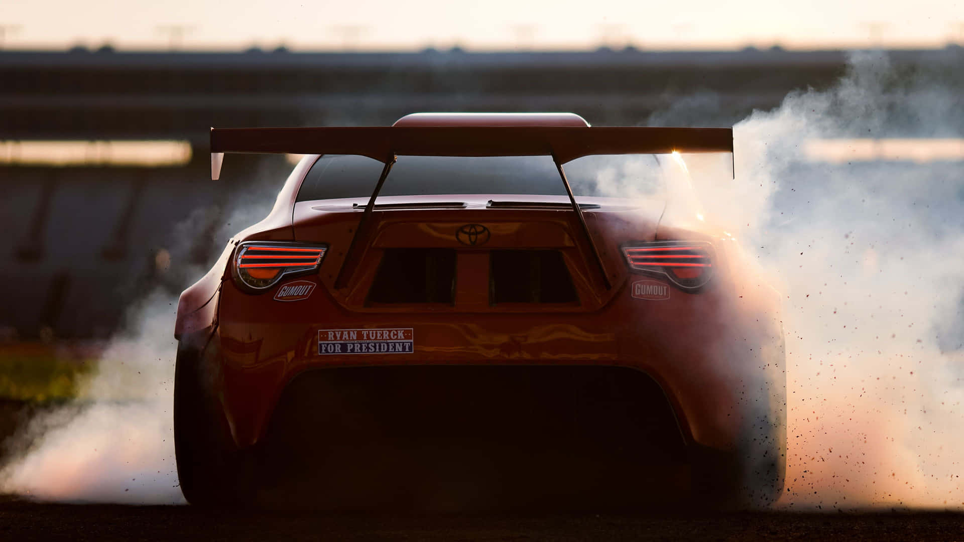 紅色賽車在日落時分的賽道上冒煙漂移。 — Toyota Supra Mk4 壁紙