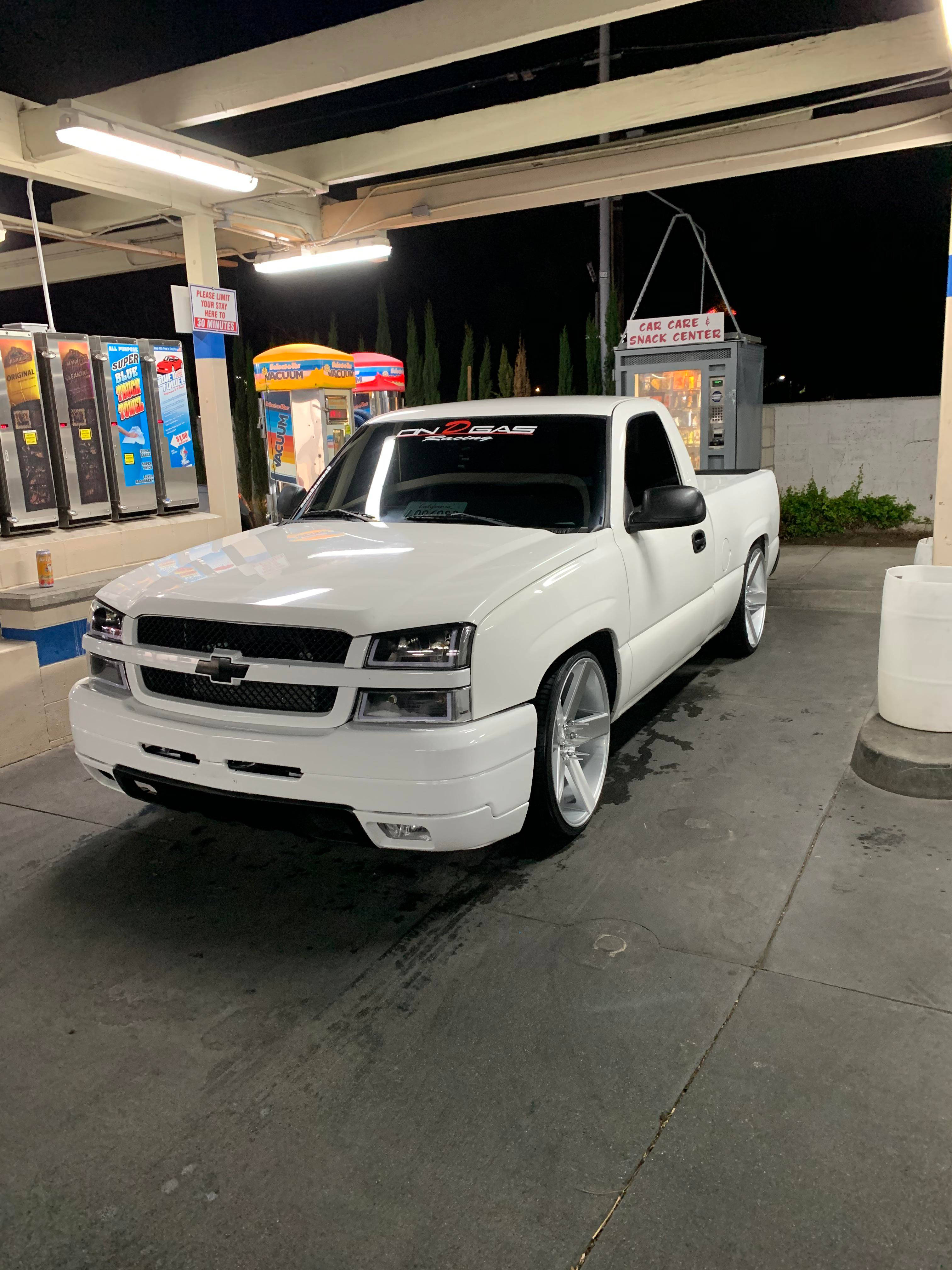 Trucks 桌布 壁紙 — 一輛帶有定制輪圈的雪佛蘭白色皮卡車停在夜間加油站的明亮燈光下。