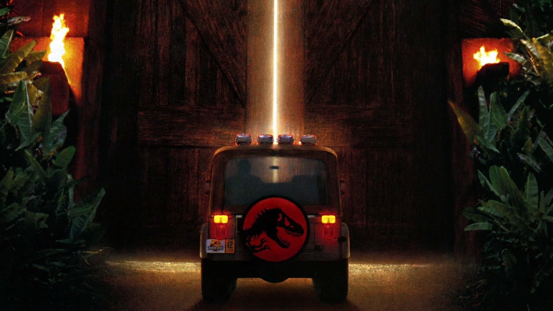Jurassic Park Zoom 桌布 壁紙 — 一輛帶有恐龍標誌的吉普車駛向一扇巨大的木門，木門被光束照亮，兩側有火炬，周圍是叢林環境。
