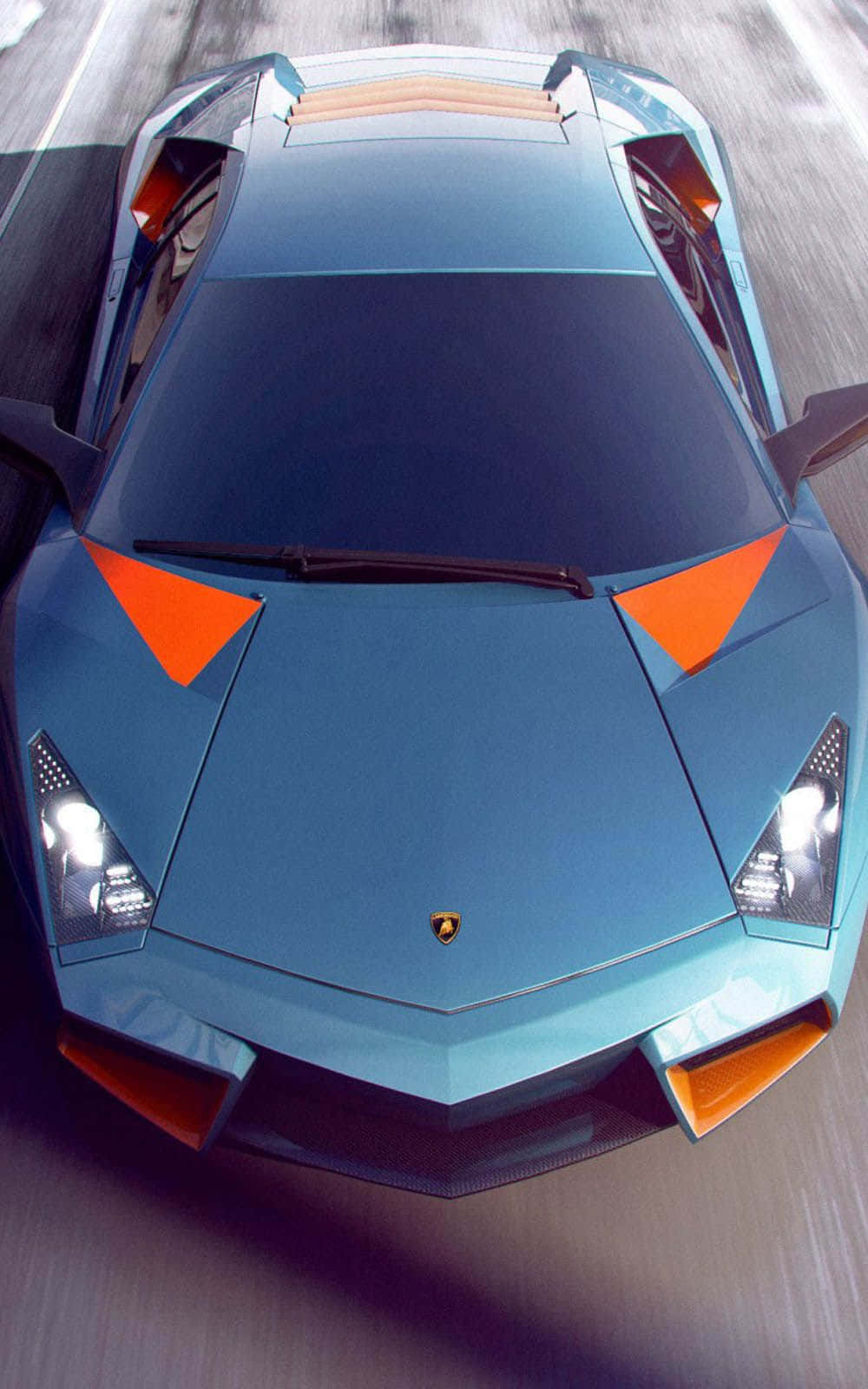 Pixel 3xl Lamborghini 桌布 壁紙 — 一輛帶有橙色裝飾的藍色藍寶堅尼在模糊的道路上疾馳的俯視圖。