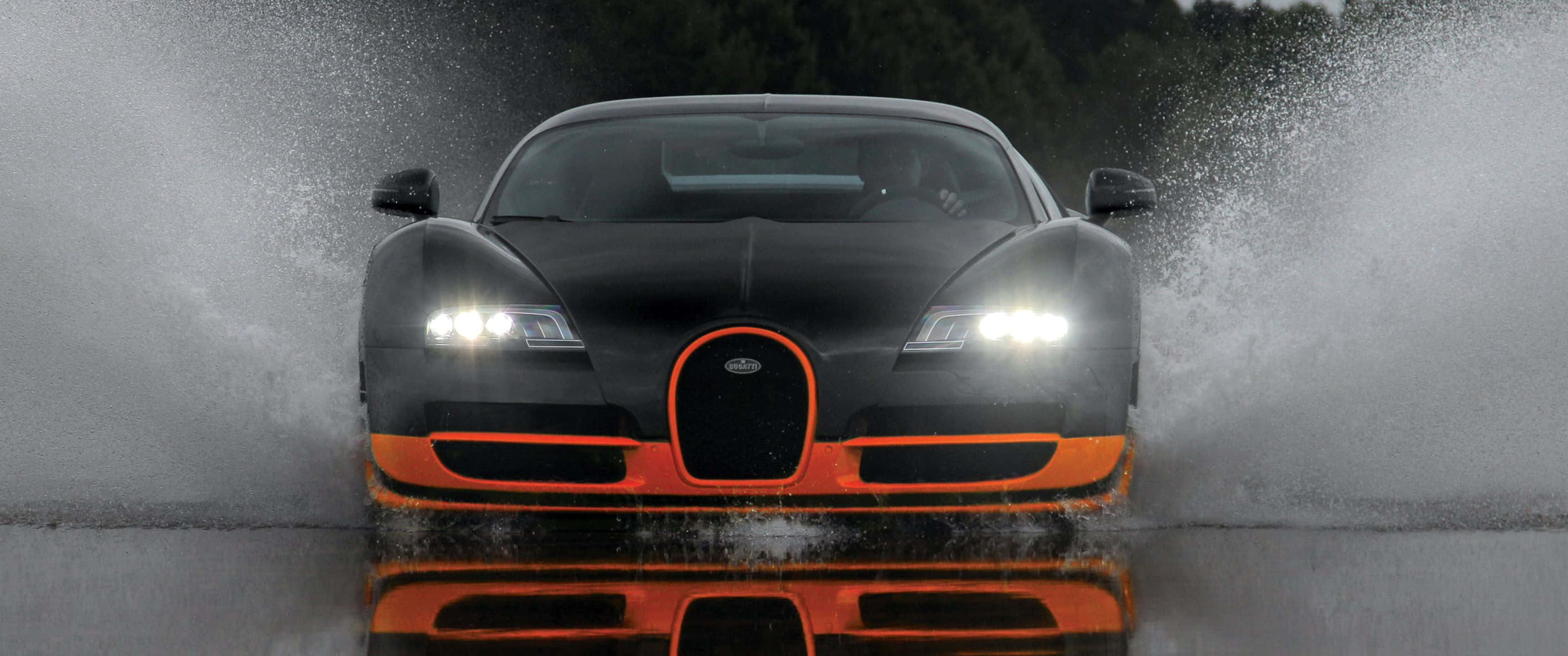 3440x1440p Bugatti 桌布 壁紙 — 一輛帶有橙色裝飾的黑色布加迪在行駛中激起水花，輪胎濺起的水花極具戲劇性。