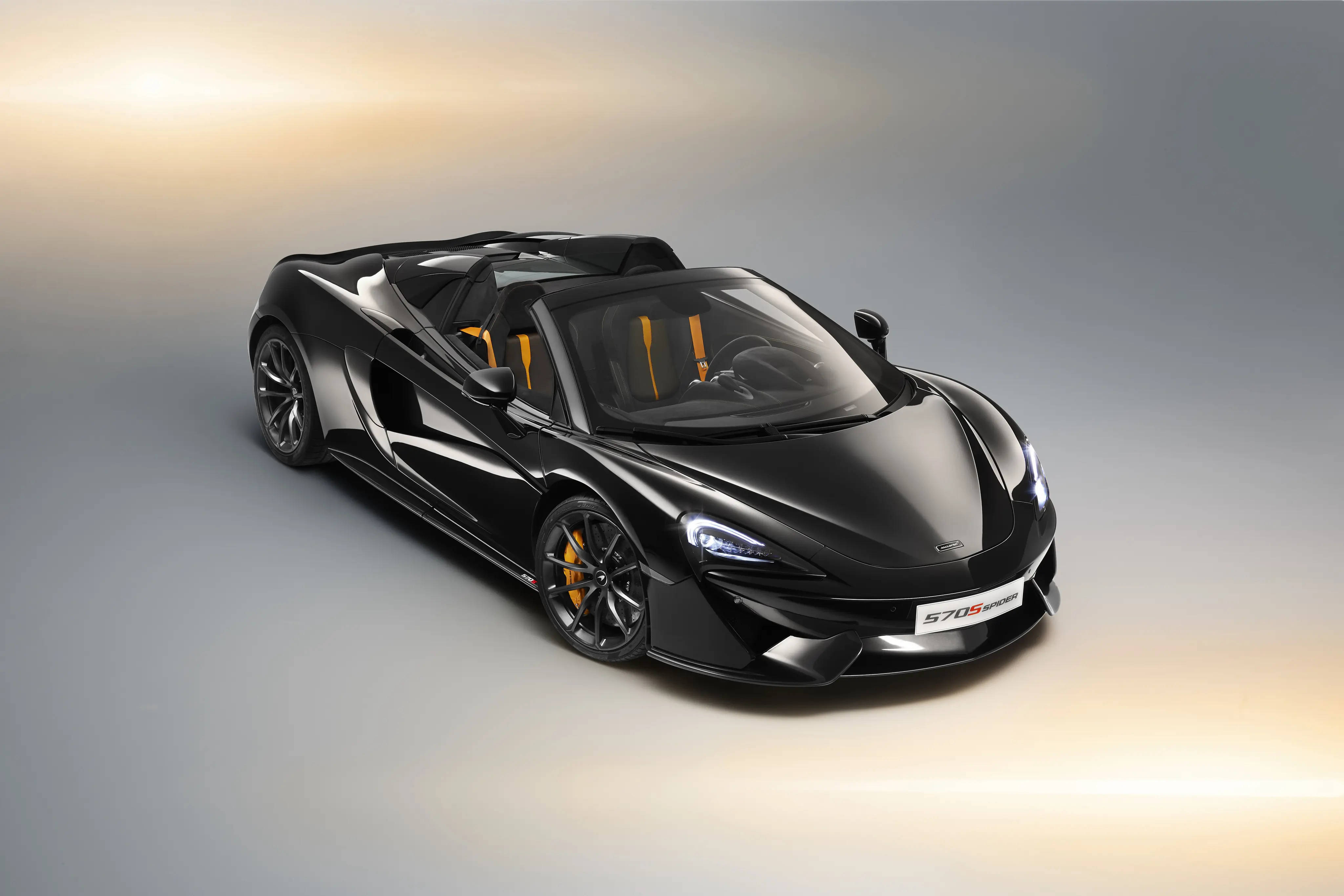 跑車 桌布 壁紙 — 一輛帶有橙色點綴的時尚黑色McLaren 570S Spider在柔和的攝影棚燈光下閃閃發光。