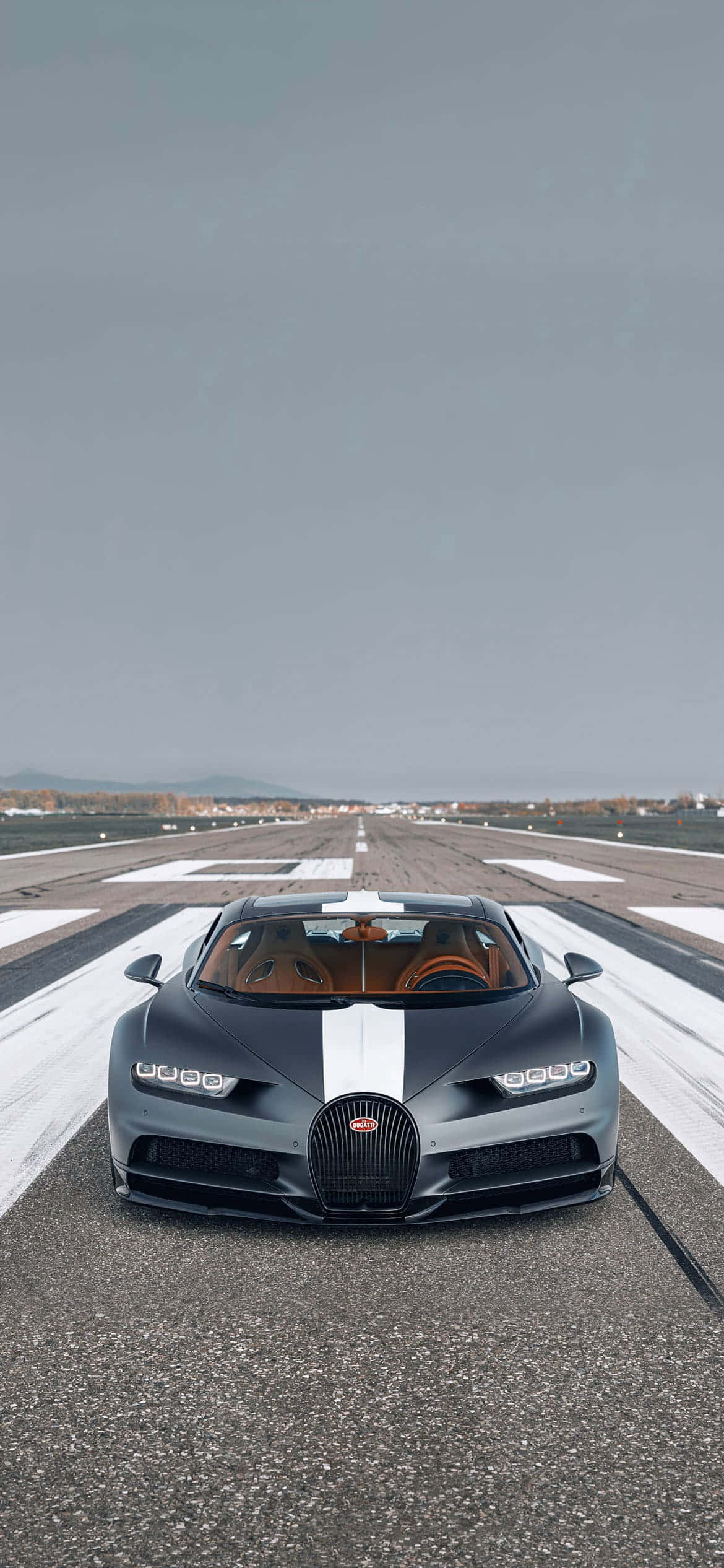 Bugatti Phone 桌布 壁紙 — 一輛帶有白色條紋的時尚灰色Bugatti超跑停在空曠的跑道上，頭頂是廣闊的灰色天空。