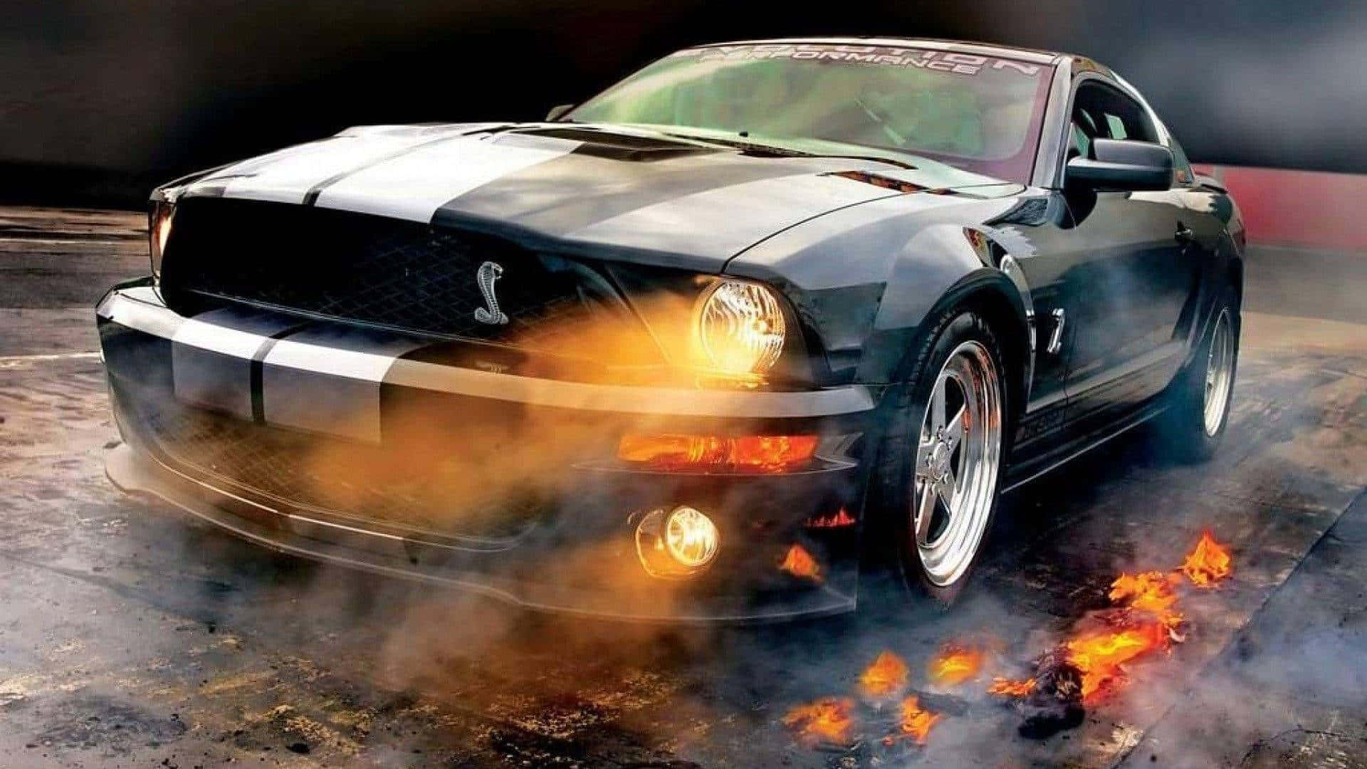 高清汽車 桌布 壁紙 — 一輛帶有白色條紋的黑色福特野馬Shelby在潮濕的瀝青賽道上燒胎並噴出火焰。