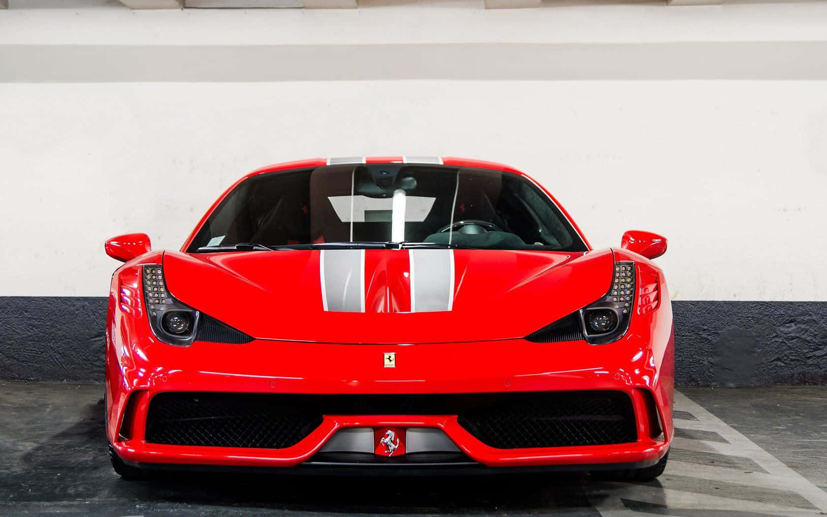 Ferrari 458 Speciale 桌布 壁紙 — 一輛帶有白色賽車條紋的光澤紅色法拉利跑車停放在室內，正面朝前，具有侵略性造型和標誌性的躍馬標誌。