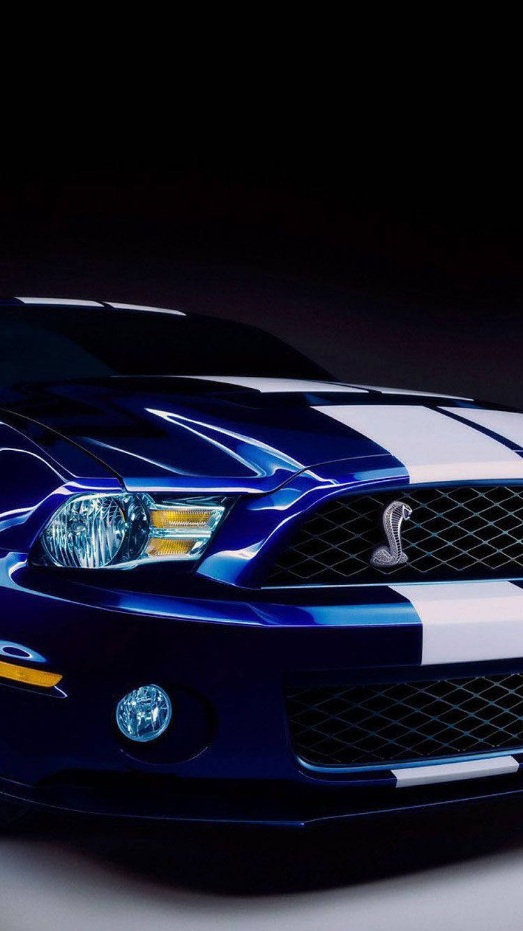 跑車 桌布 壁紙 — 一輛帶有白色賽車條紋的光澤藍色Shelby Cobra跑車在黑色背景下的戲劇性工作室燈光中閃耀。