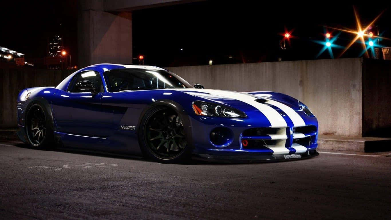 Dodge 桌布 壁紙 — 一輛帶有白色賽車條紋的光澤藍色道奇Viper，夜晚停在城市環境中的霓虹燈下。