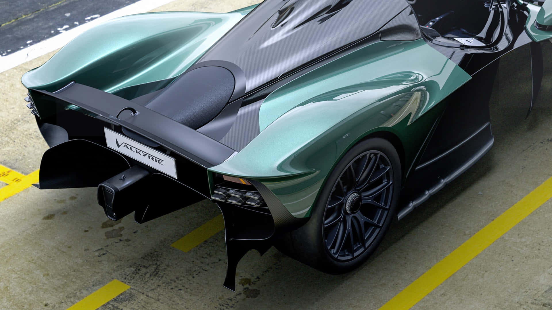 奧斯頓馬丁 桌布 壁紙 — 一輛帶有碳纖維飾邊的時尚綠色Aston Martin Valkyrie超跑，停放在標有黃線的混凝土表面上。