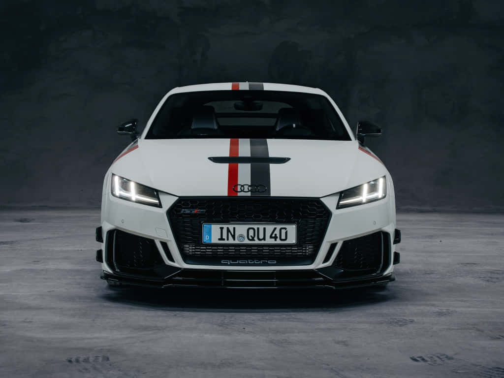 Audi Tt Rs 桌布 壁紙 — 一輛帶有紅色和黑色賽車條紋的白色奧迪TT RS在昏暗的混凝土工作室中向前凝視。