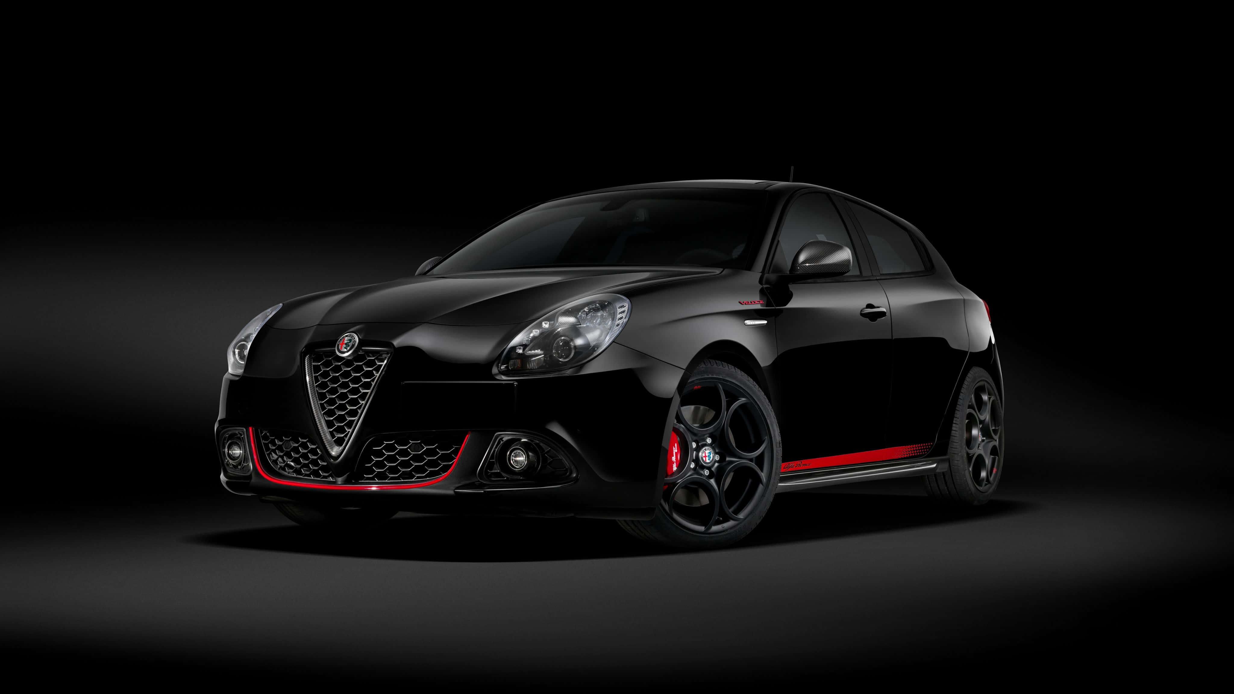 Alfa Romeo Giulietta 桌布 壁紙 — 一輛帶有紅色點綴的時尚黑色愛快羅密歐跑車在深色背景的攝影棚燈光下閃耀。