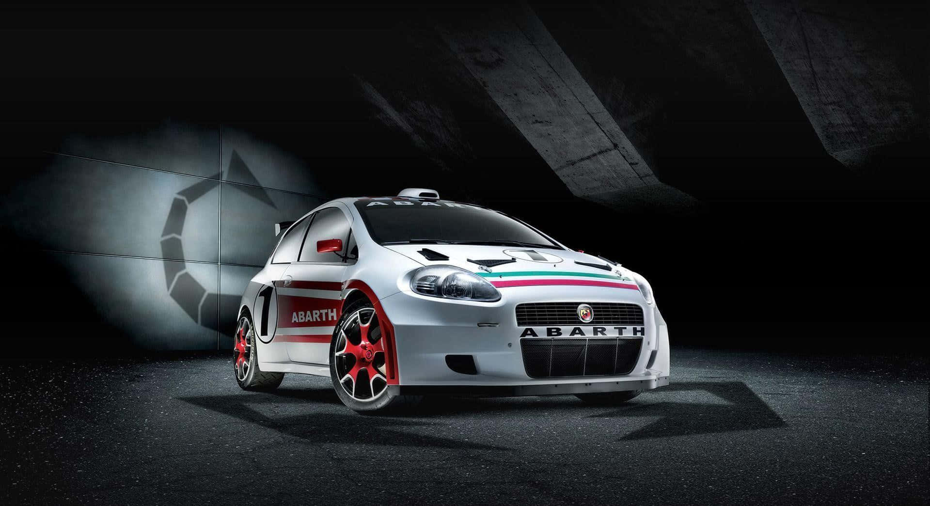 Abarth 桌布 壁紙 — 一輛帶有紅色點綴的白色 Abarth 拉力賽車在黑暗的混凝土隧道中被戲劇性地照亮。