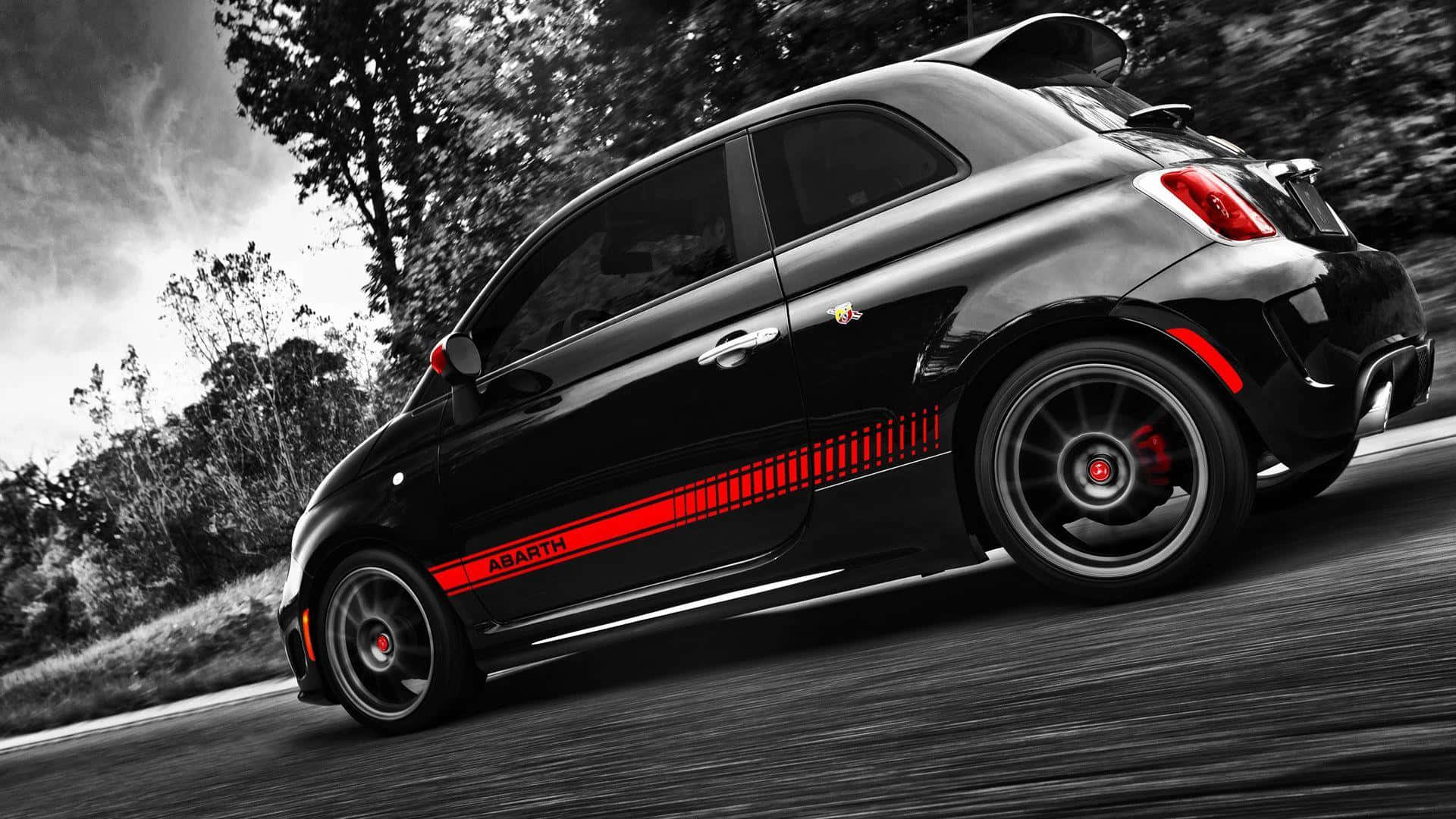 Abarth 桌布 壁紙 — 一輛帶有紅色點綴的黑色Abarth汽車在選擇性色彩的模糊森林背景下行駛。