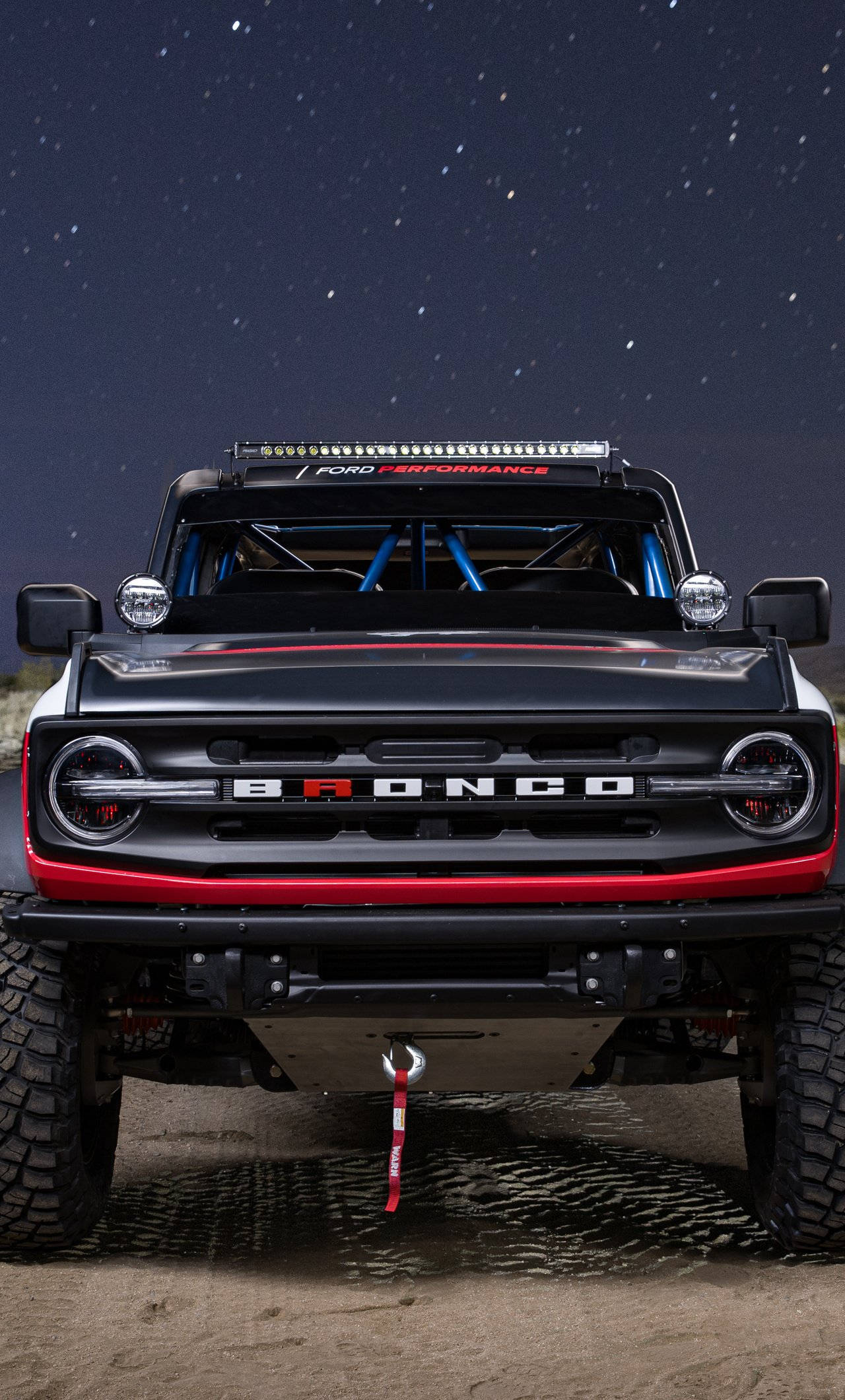 Ford Bronco 桌布 壁紙 — 一輛帶有紅色點綴的黑色福特Bronco正面朝向沙地，在星空夜空下。
