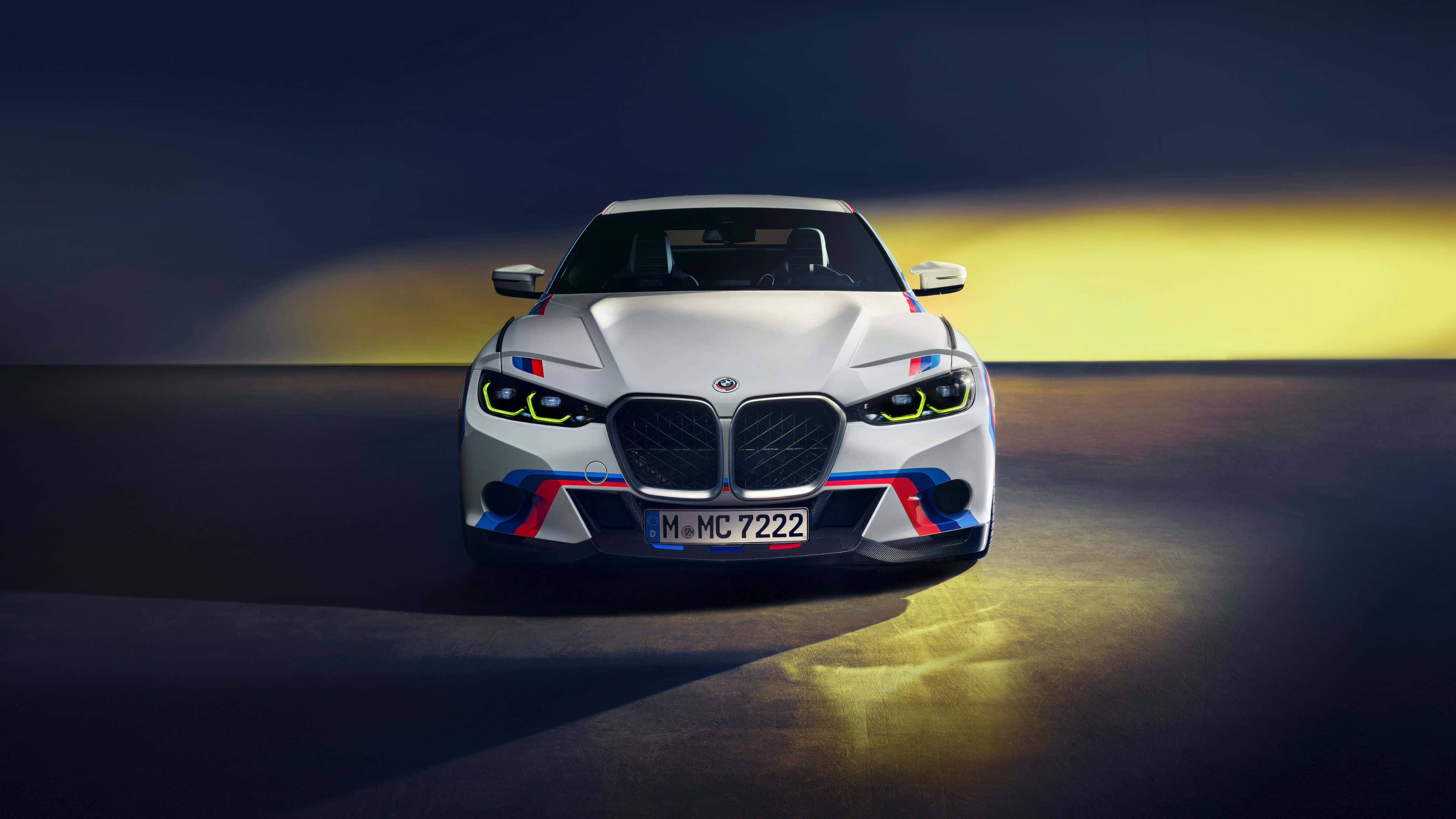 4K BMW 壁紙 桌布 壁紙 — 一輛帶有紅藍色調的白色BMW M2跑車在戲劇性的金色燈光下，面向黑暗漸變背景向前。