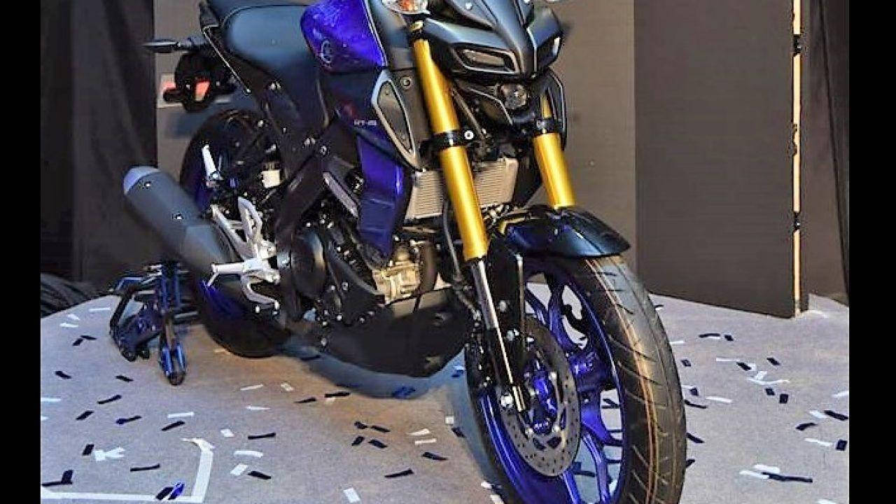 yamaha mt 15 桌布 壁紙 — 一輛帶有紫色和金色點綴的時尚運動機車，停放在工作室內鋪滿五彩紙屑的地板上。