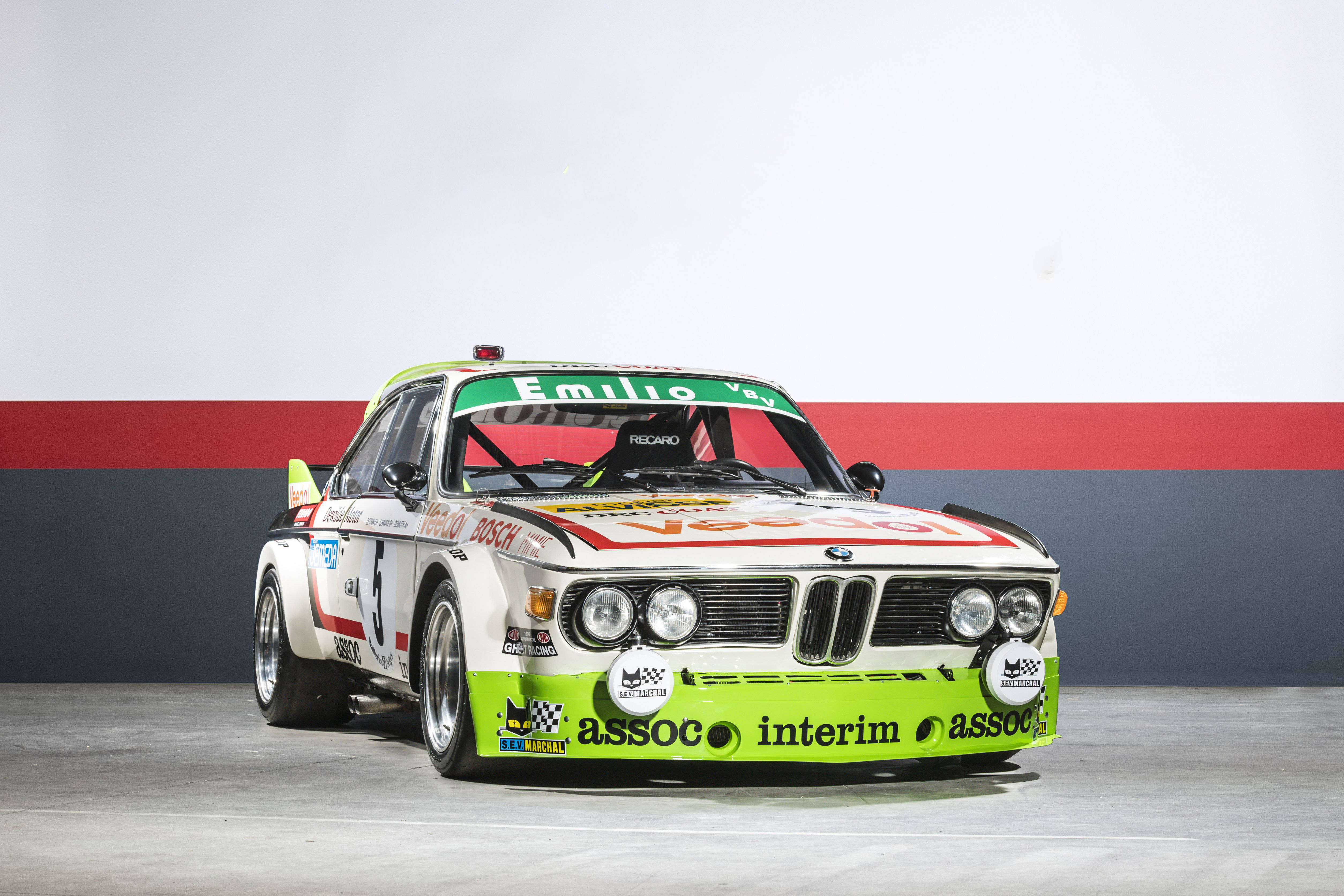 classic bmw 桌布 壁紙 — 一輛帶有綠色和紅色點綴的復古白色BMW賽車在紅色和灰色牆壁背景的工作室中展示。