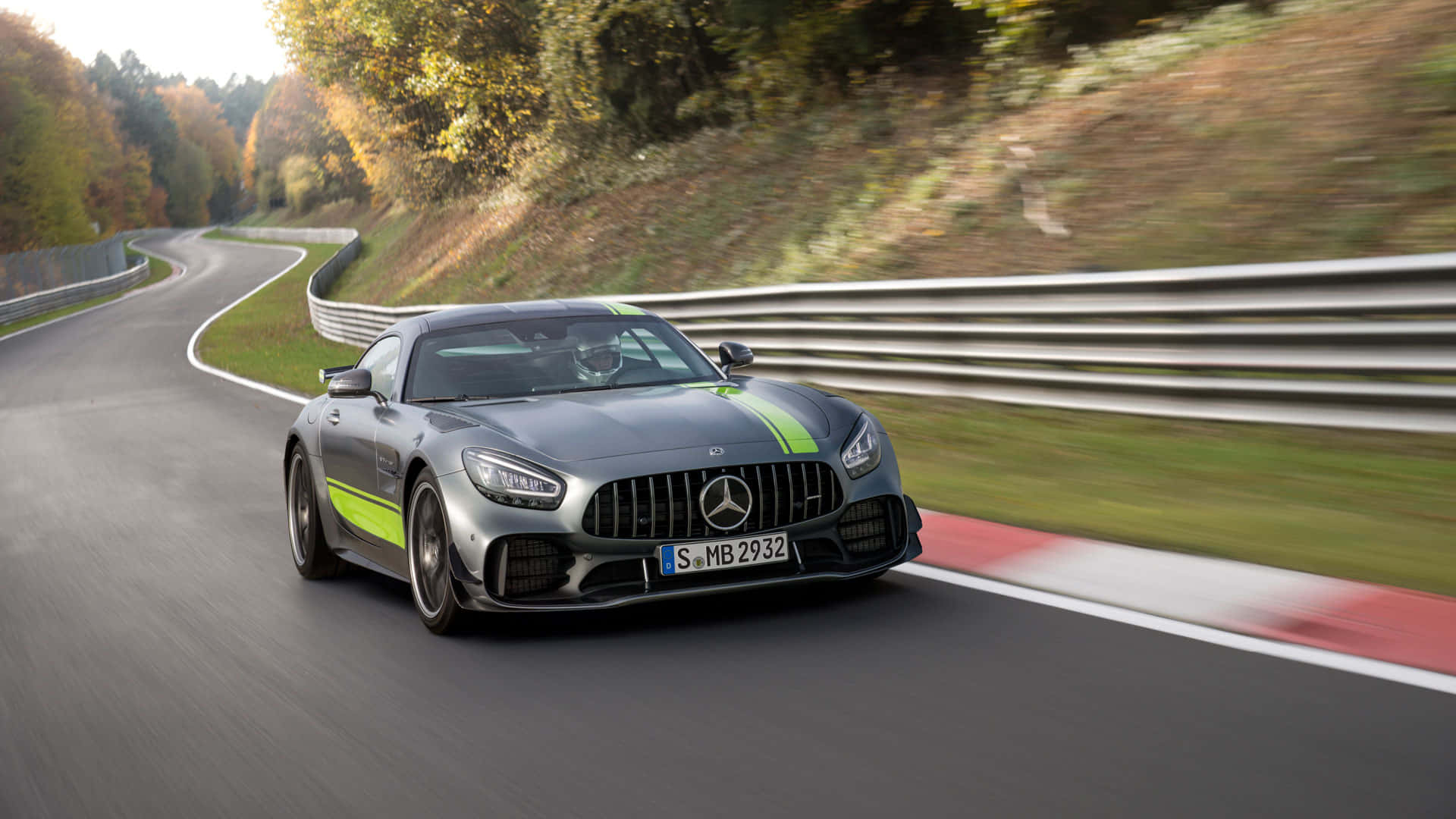 汽車 桌布 壁紙 — 一輛帶有綠色點綴的時尚銀色 Mercedes-AMG GT 在蜿蜒的秋季森林道路上奔馳。