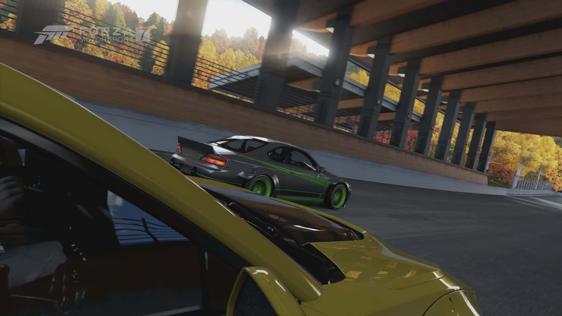 race 桌布 壁紙 — 一輛帶有綠色點綴的銀色跑車在混凝土天橋下飄移，秋天的樹木在陽光下閃耀。