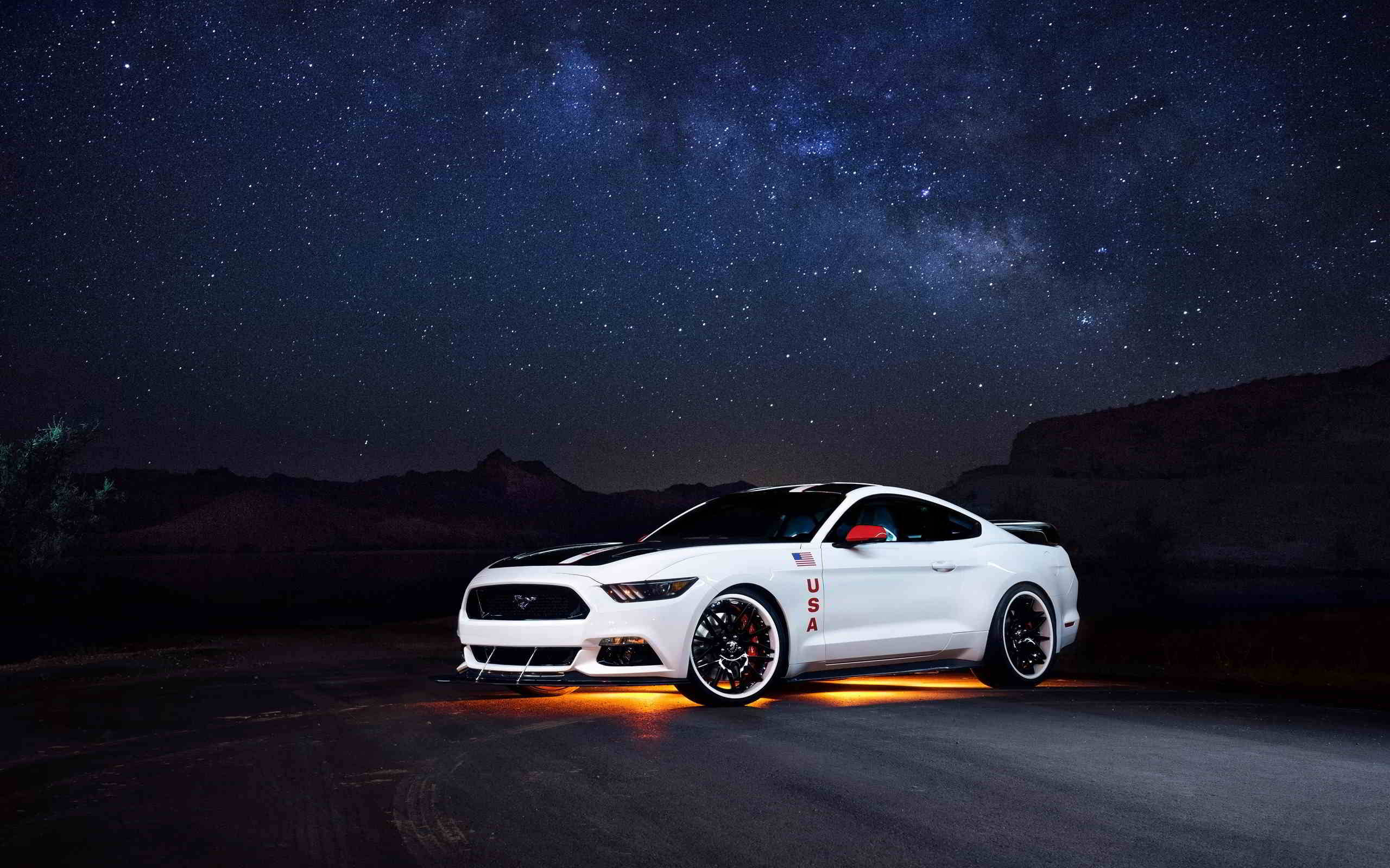 cars 桌布 壁紙 — 一輛帶有美國貼紙的白色福特野馬在星空下閃耀，銀河橫跨沙漠山脈之上。