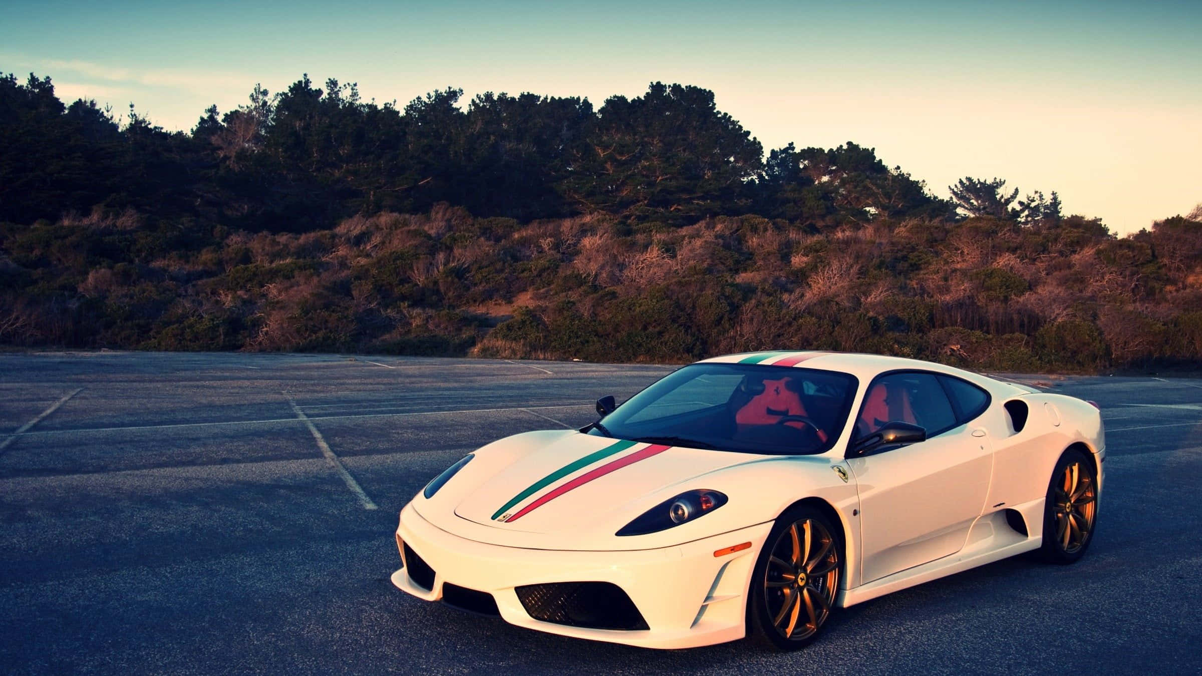 Ferrari F430 桌布 壁紙 — 一輛帶有義大利國旗條紋的白色法拉利跑車，在日落時分停泊在瀝青停車場，背景有樹木。