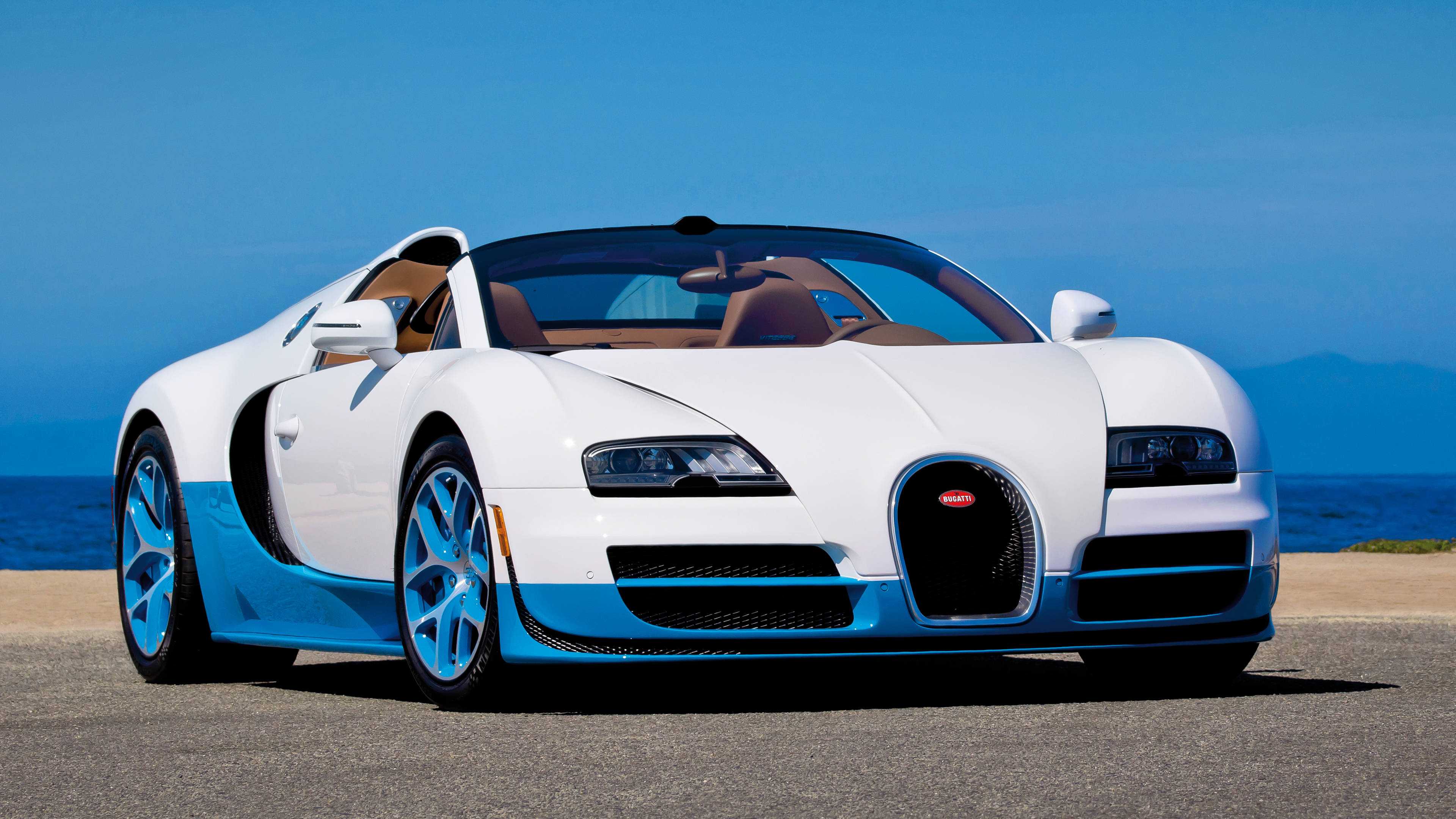 Cool Bugatti 桌布 壁紙 — 一輛帶有藍色裝飾的純白色Bugatti Veyron停泊在海岸公路上，天空清澈湛藍。