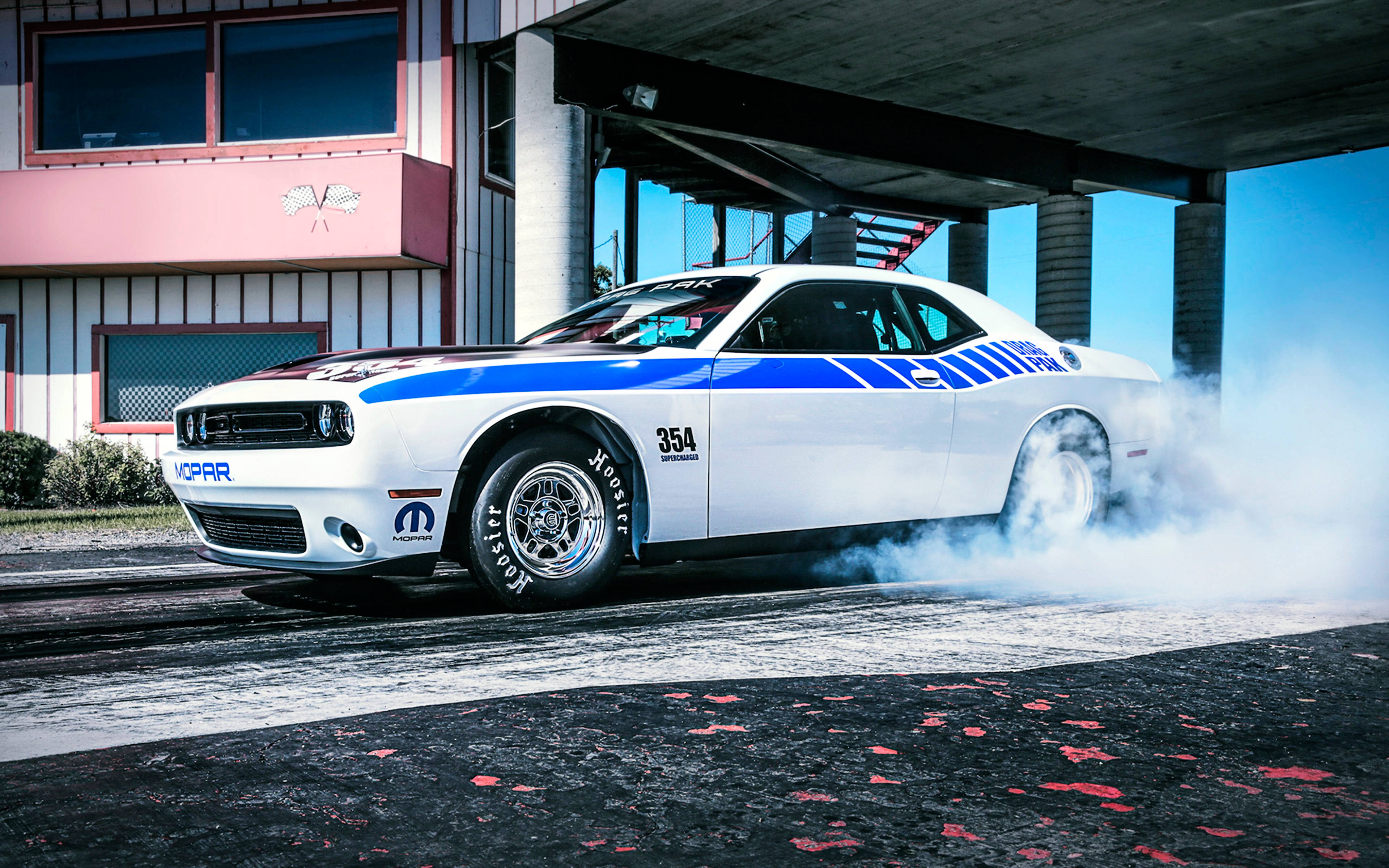 Challenger 桌布 壁紙 — 一輛帶有藍色賽車條紋的白色道奇挑戰者在混凝土天橋下漂移燒胎。