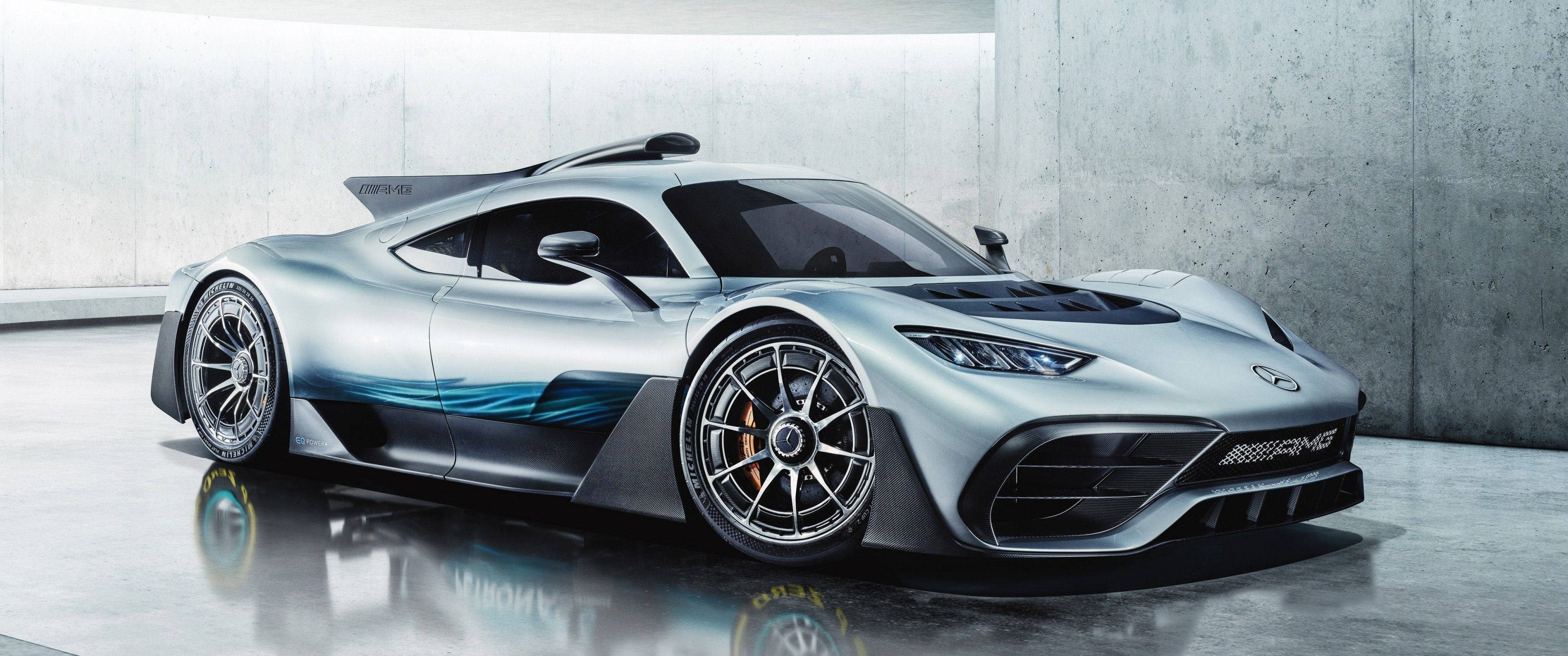 Mercedes 桌布 壁紙 — 一輛帶有藍色點綴的時尚銀色 Mercedes-AMG One 超跑在簡約混凝土車庫的攝影棚燈光下閃耀。