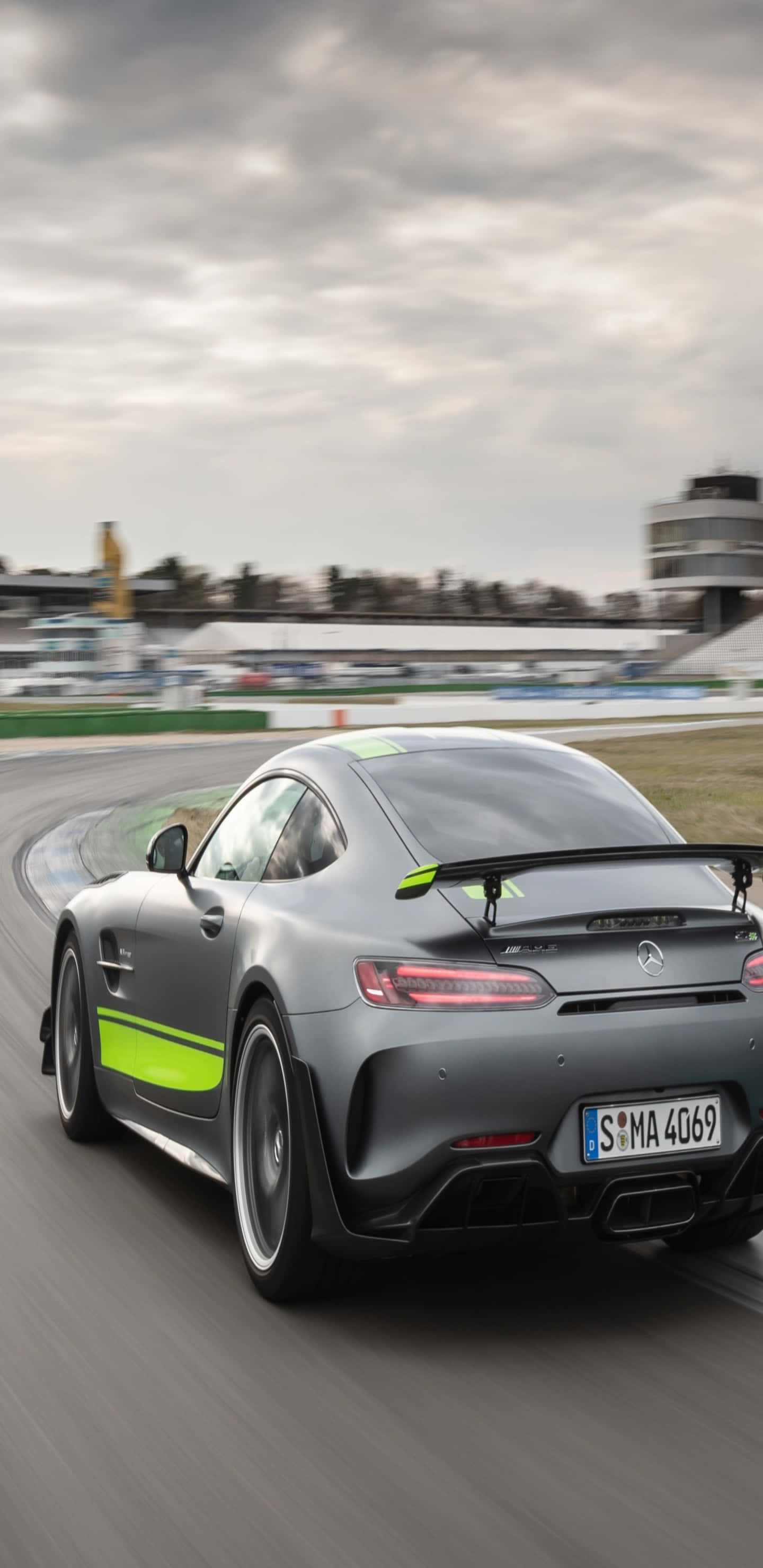 Car Images HD 桌布 壁紙 — 一輛帶有螢光綠色點綴的時尚灰色 Mercedes-AMG GT R 在陰天下的潮濕賽道上奔馳。
