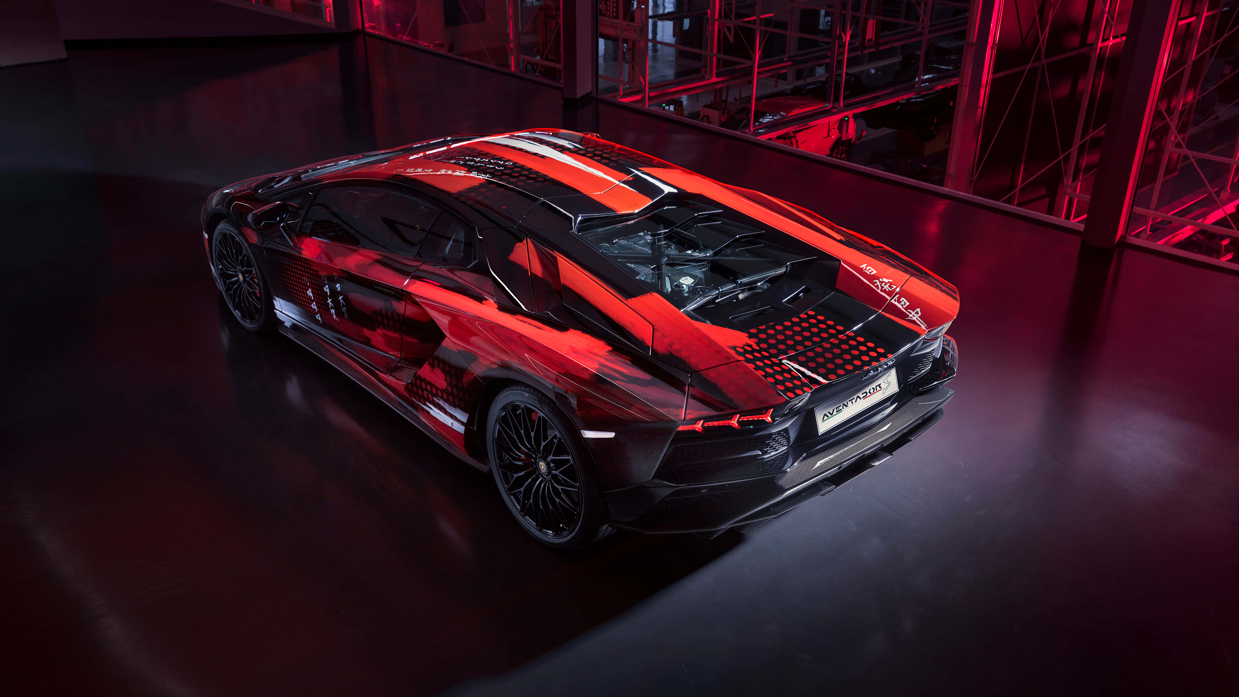 黑色 桌布 壁紙 — 一輛帶有賽車條紋的時尚紅黑 Lamborghini Aventador SVJ 在現代工業車庫的戲劇性紅光下閃閃發光。