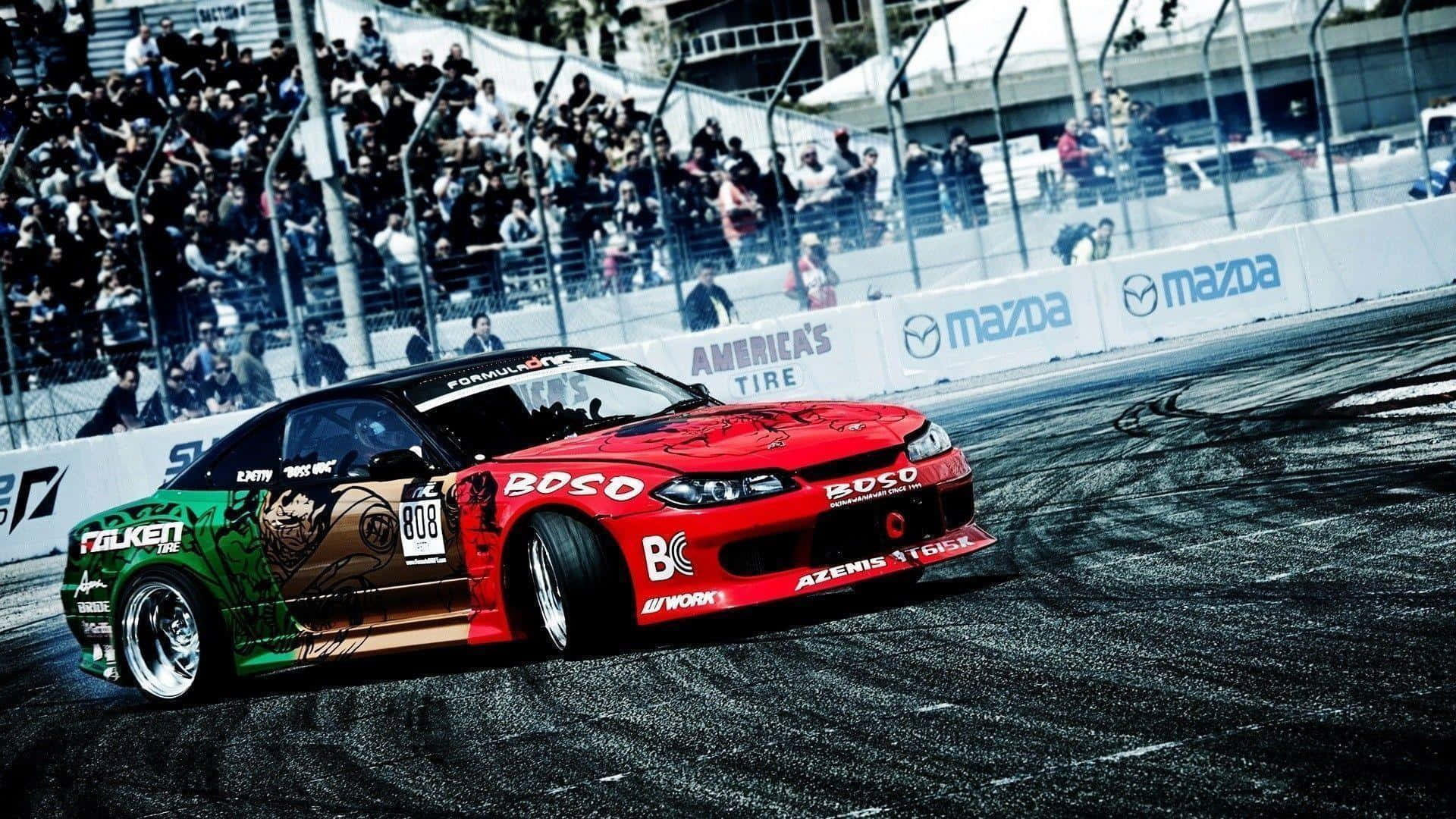 race car 桌布 壁紙 — 一輛帶有醒目圖案的紅綠飄移車在賽道上側滑，觀眾從看台上觀看。