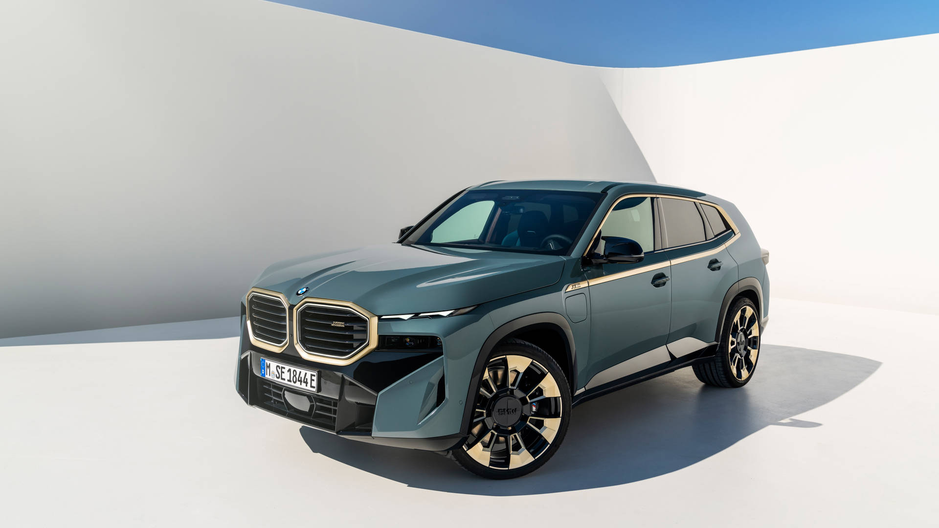 一輛在白色工作室環境中帶有金色飾邊的綠色寶馬電動SUV。