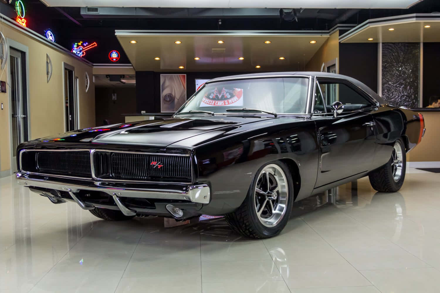 1969 年道奇 Charger 桌布 壁紙 — 一輛帶有鍍鉻裝飾的光澤黑色經典肌肉車在展廳燈光下閃閃發光，映照在反光地板上。
