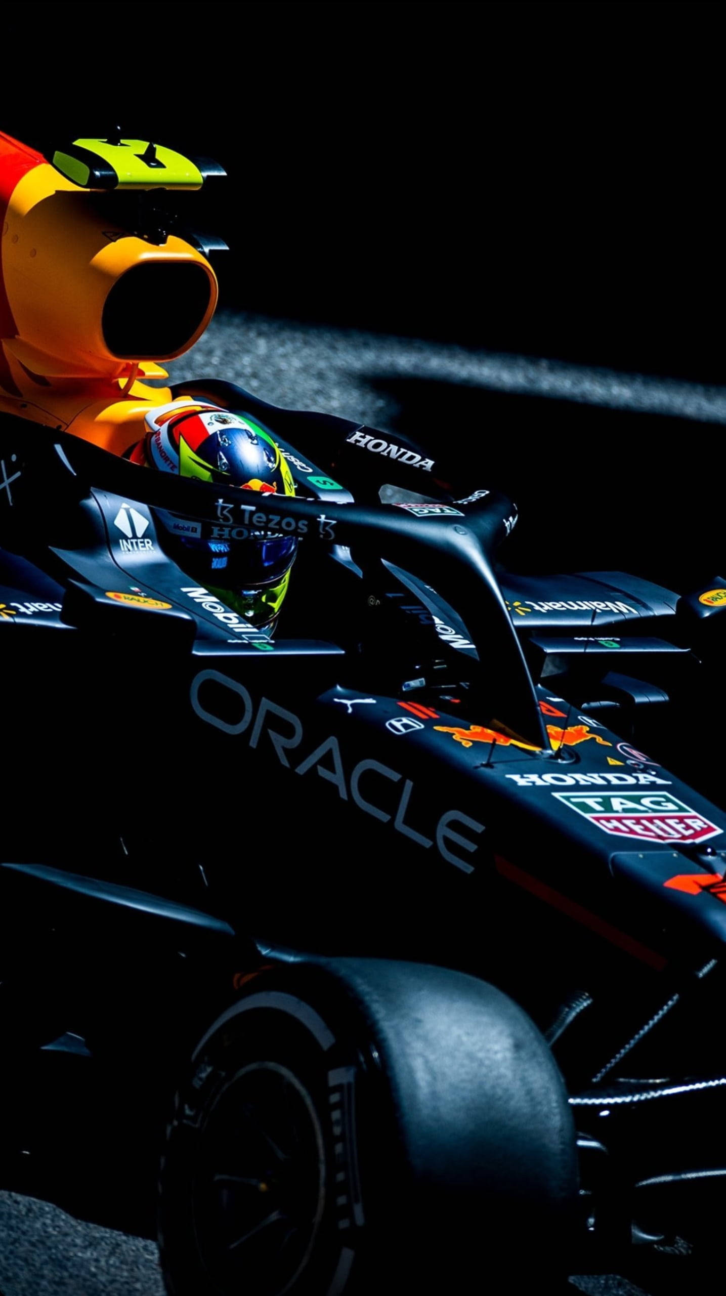 sergio perez 桌布 壁紙 — 一輛帶有頭盔車手的一級方程式賽車在黑暗賽道上於戲劇性的聚光燈下發光。