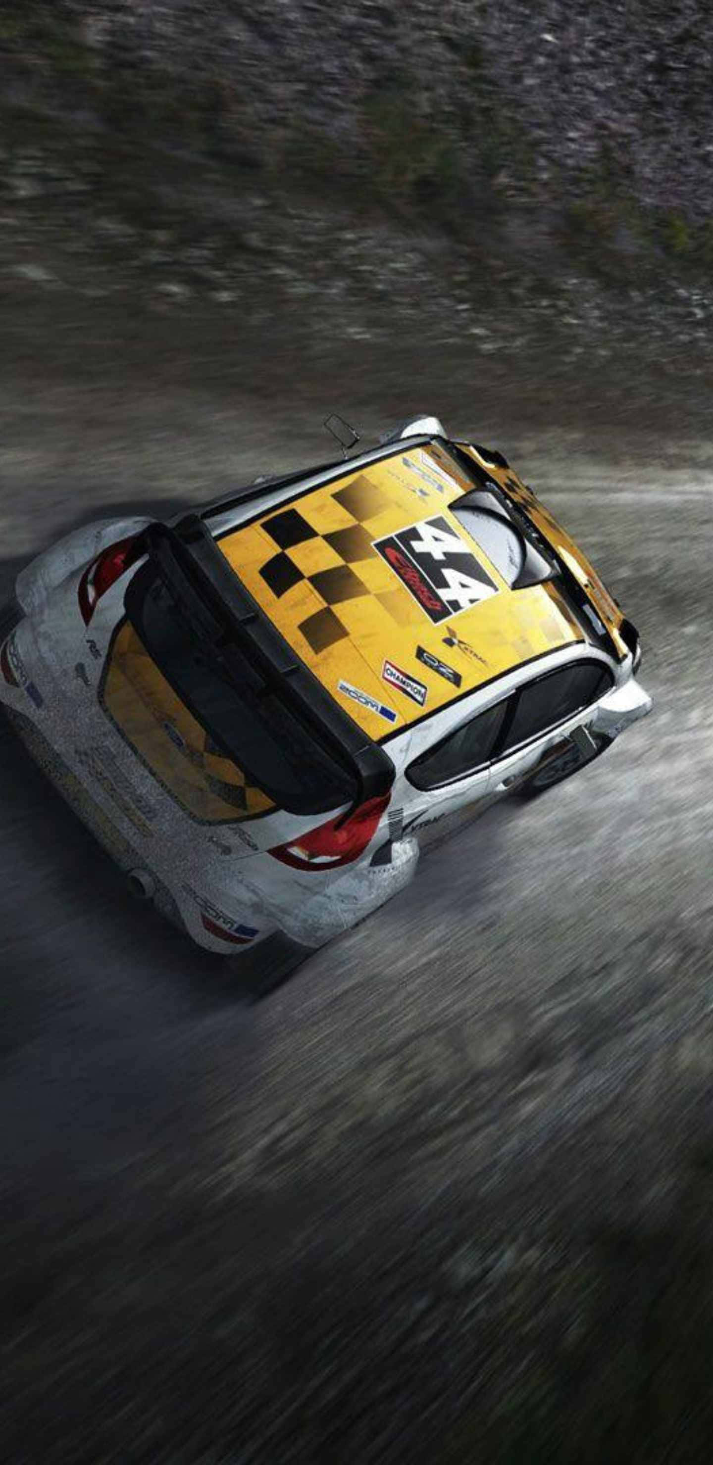 Android Dirt Rally 桌布 壁紙 — 一輛帶有黃色格子車頂的拉力賽車在泥濘的森林賽道上從上方視角飛馳。