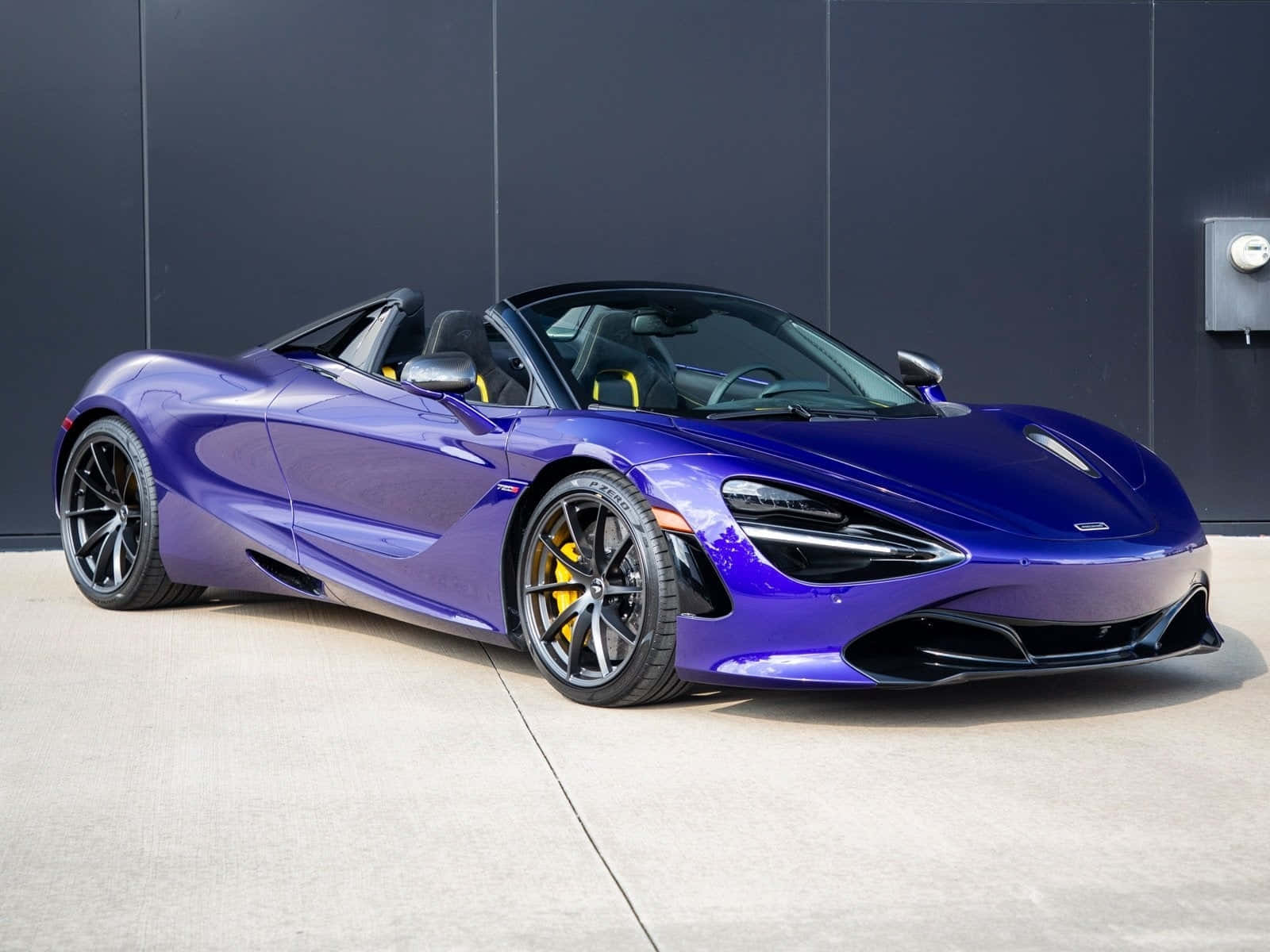 汽車 桌布 壁紙 — 一輛帶有黃色點綴的光澤紫色McLaren 720S Spider敞篷車停靠在深灰色牆壁旁。
