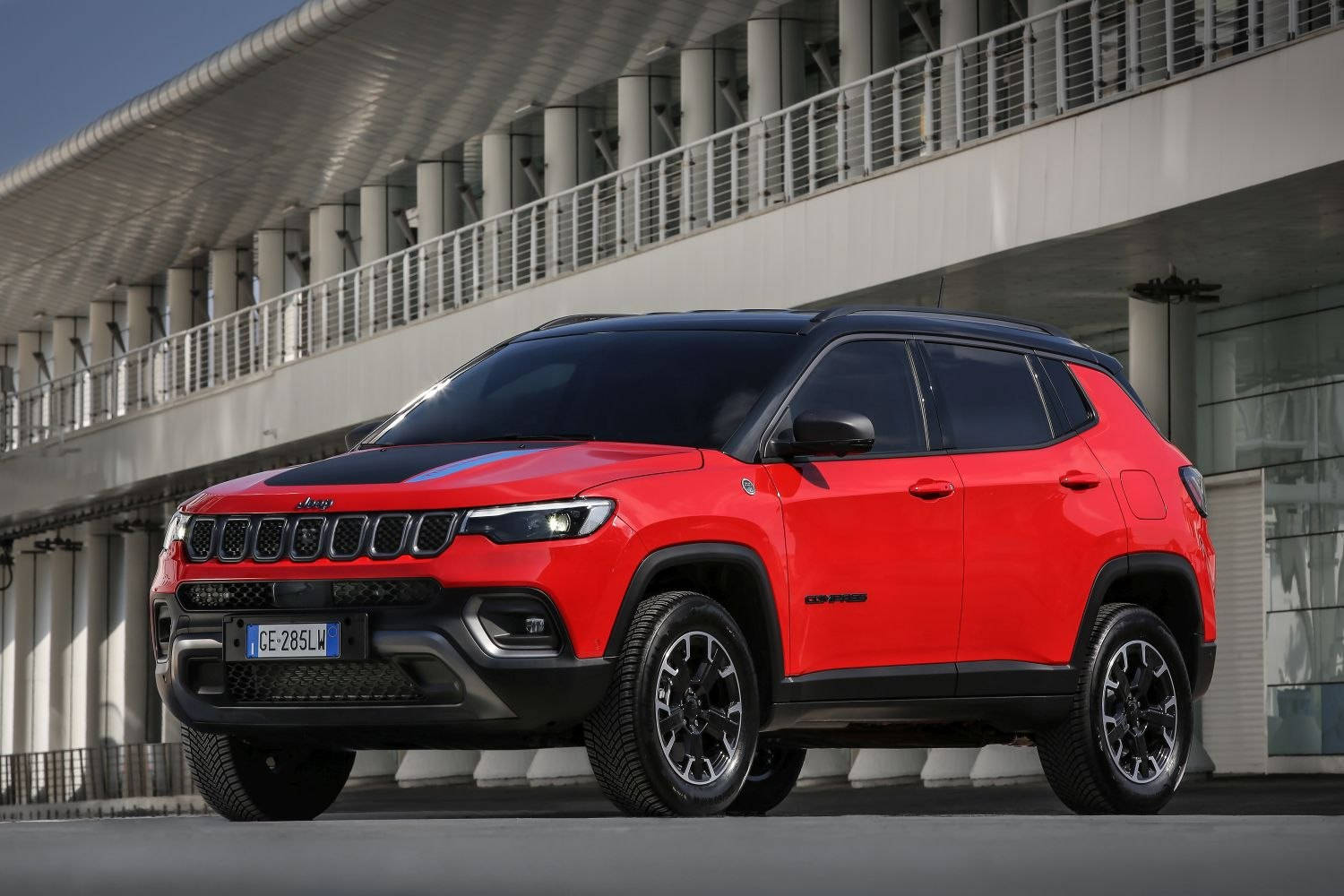 汽車 桌布 壁紙 — 一輛帶有黑色飾邊的鮮紅色Jeep Compass SUV停放在現代白色建築結構下。