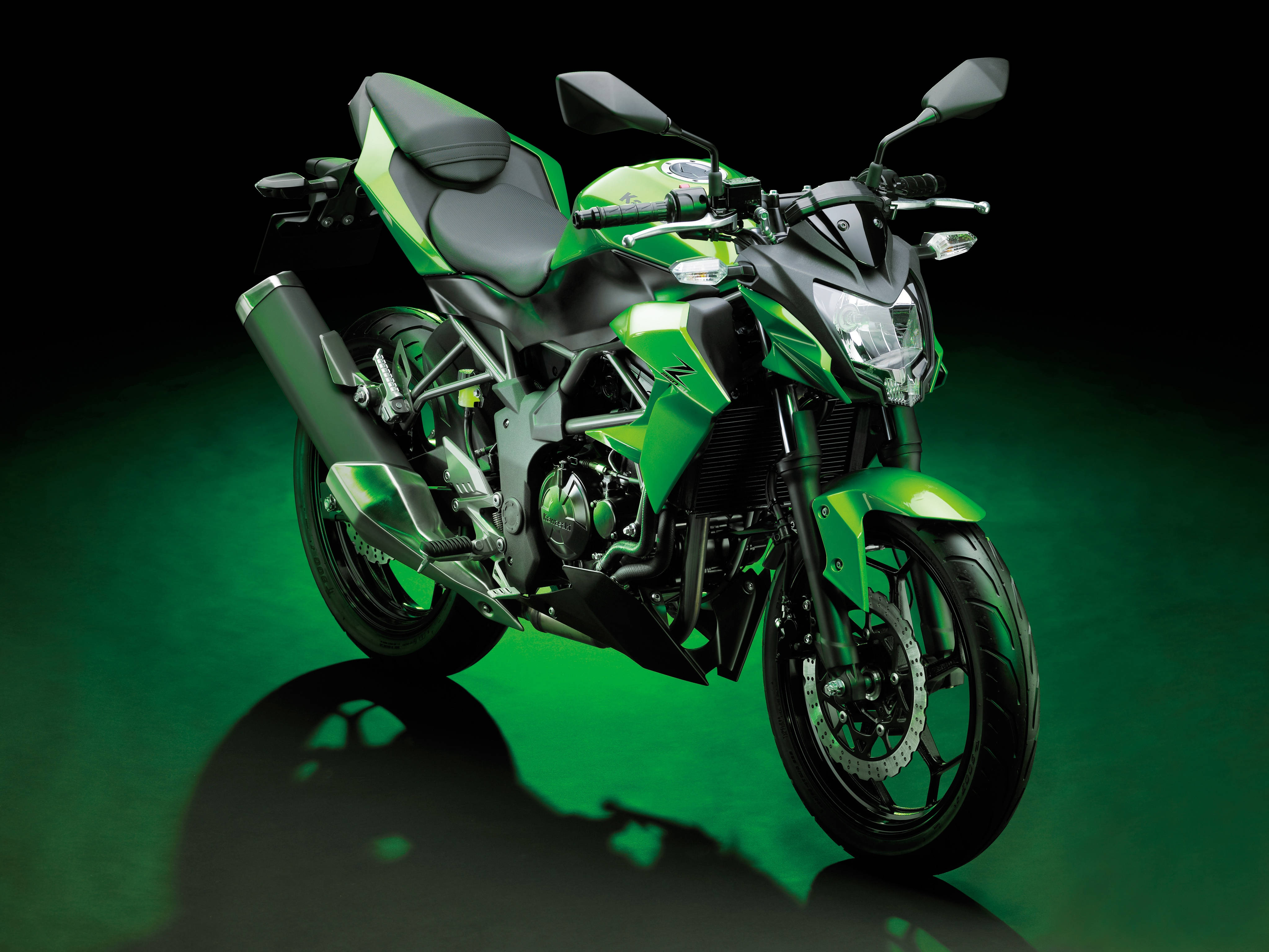 Kawasaki Desktop 桌布 壁紙 — 一輛帶有黑色點綴的時尚綠色運動摩托車，在黑暗背景和發光的綠色地板反射下，被戲劇性地照亮。
