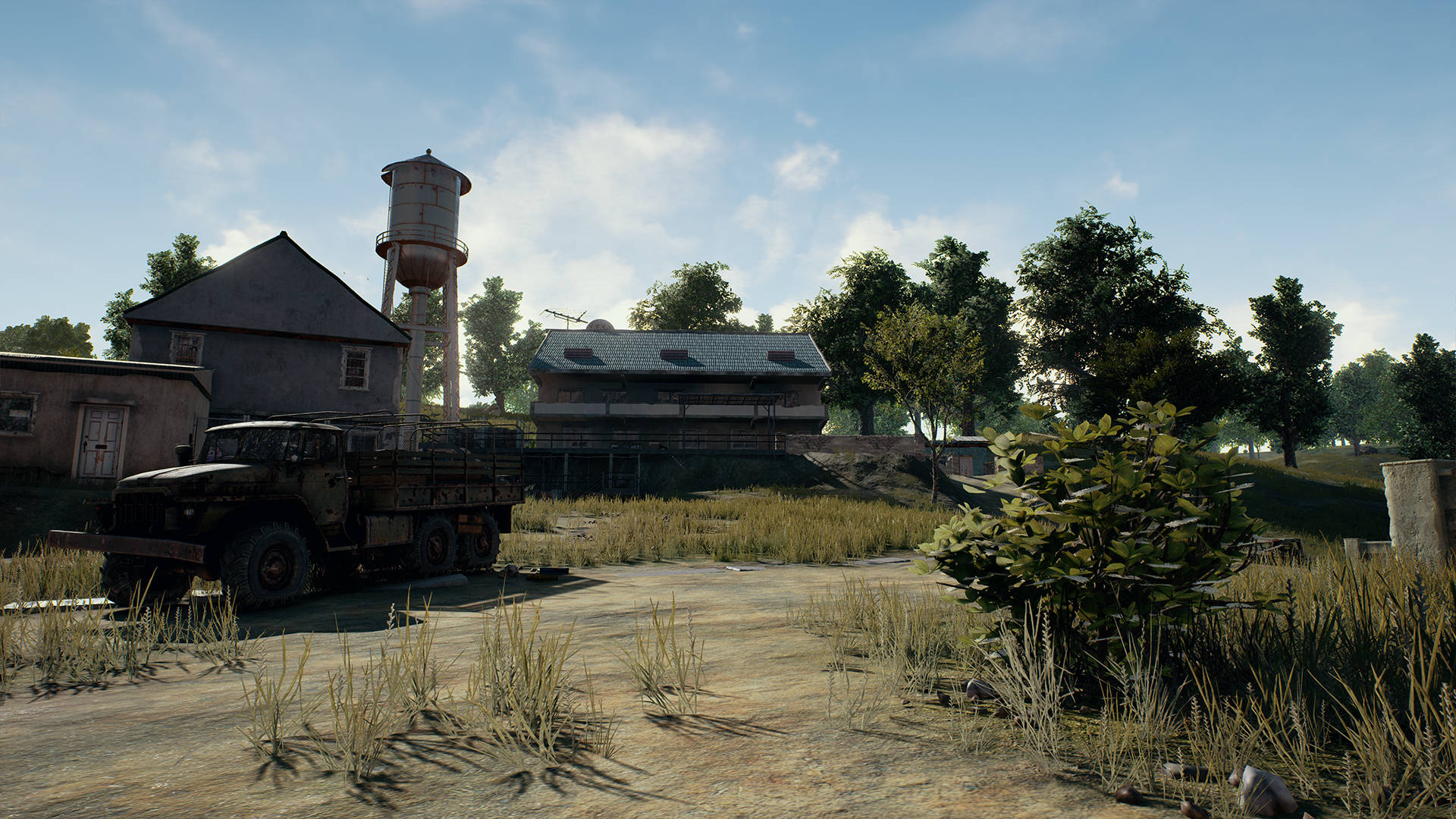 廢棄軍車在雜草叢生的田野，附近有舊建築物和水塔。 — PUBG 4K 壁紙 壁紙