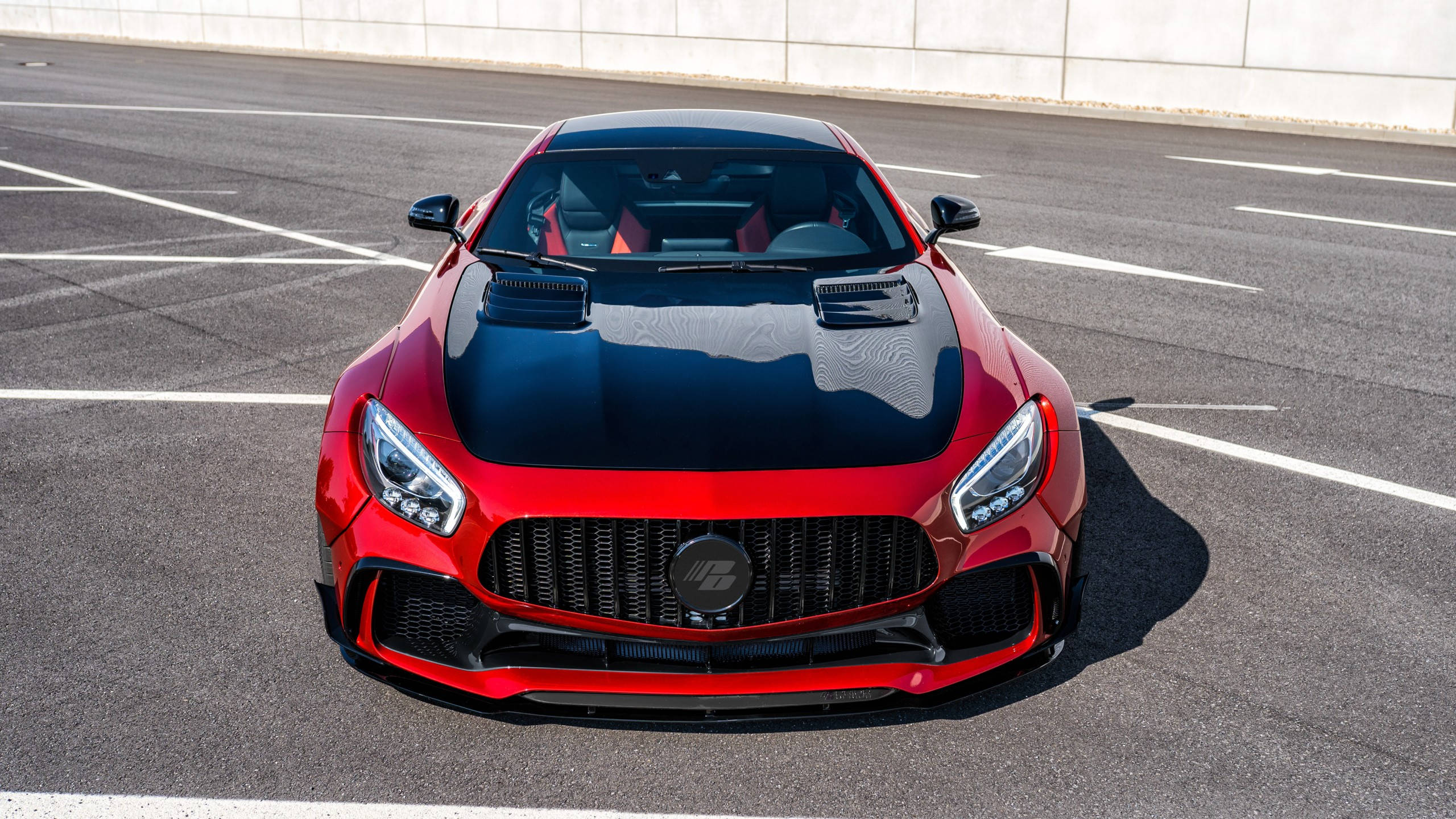 Gtr 桌布 壁紙 — 一輛引人注目的紅色 Mercedes-AMG GT R 跑車，帶有黑色引擎蓋，停放在陽光明媚的瀝青停車場上。