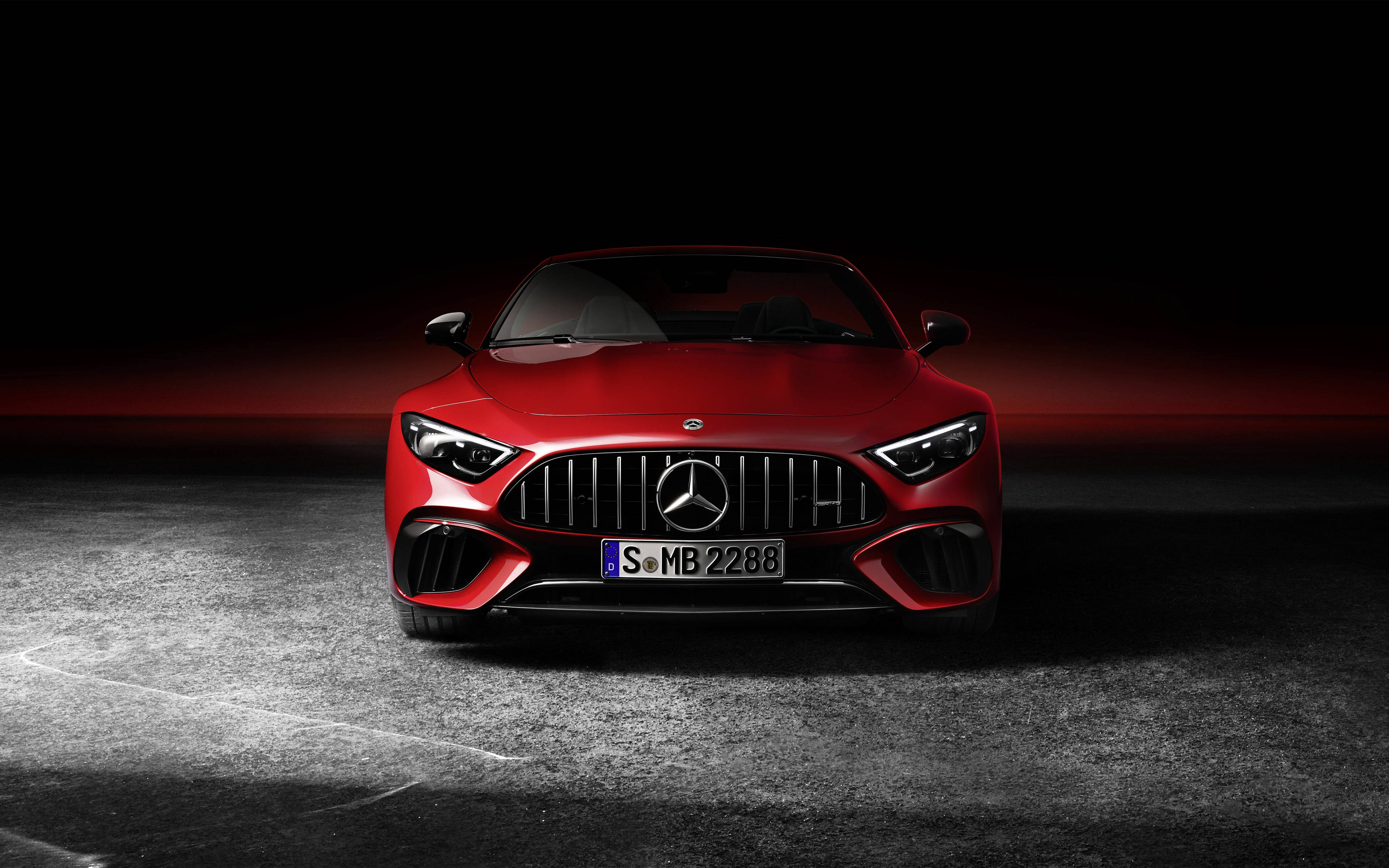 4K 奔馳壁紙 桌布 壁紙 — 一輛引人注目的紅色 Mercedes-AMG 跑車在戲劇性燈光下閃閃發光，背景是黑暗的攝影棚和發光的紅色地平線。