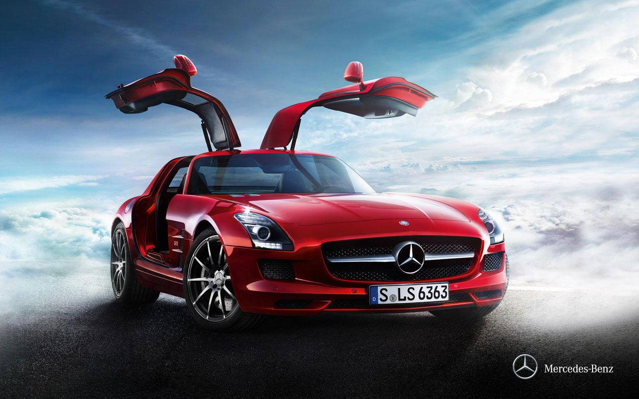 汽車 桌布 壁紙 — 一輛引人注目的紅色 Mercedes SLS AMG 跑車，鷗翼車門打開，停在一條黑暗的道路上，上方是蓬鬆的白雲，背景是戲劇性的藍天。