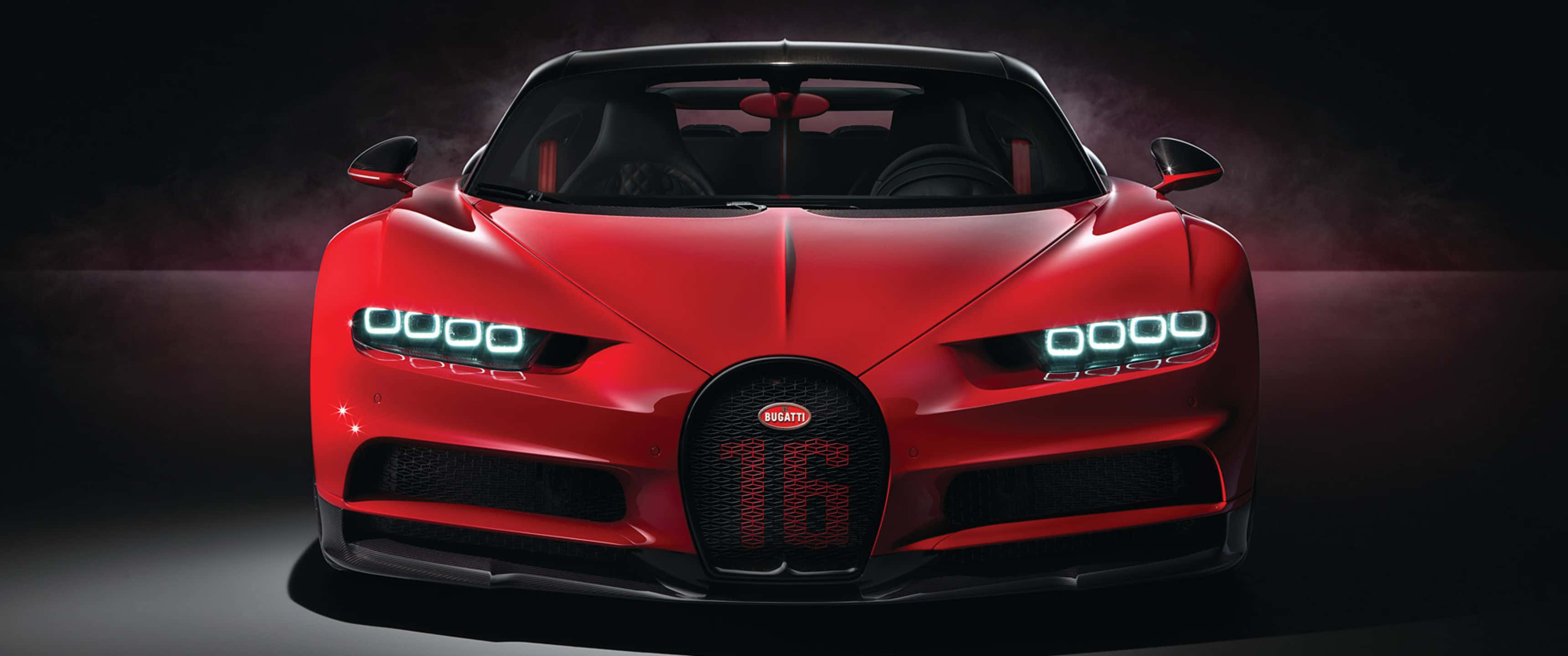 3440x1440p Bugatti 桌布 壁紙 — 一輛引人注目的紅色Bugatti Chiron Super Sport 300+在戲劇性的工作室燈光下閃耀，配備發光的頭燈和霸氣的水箱護罩。