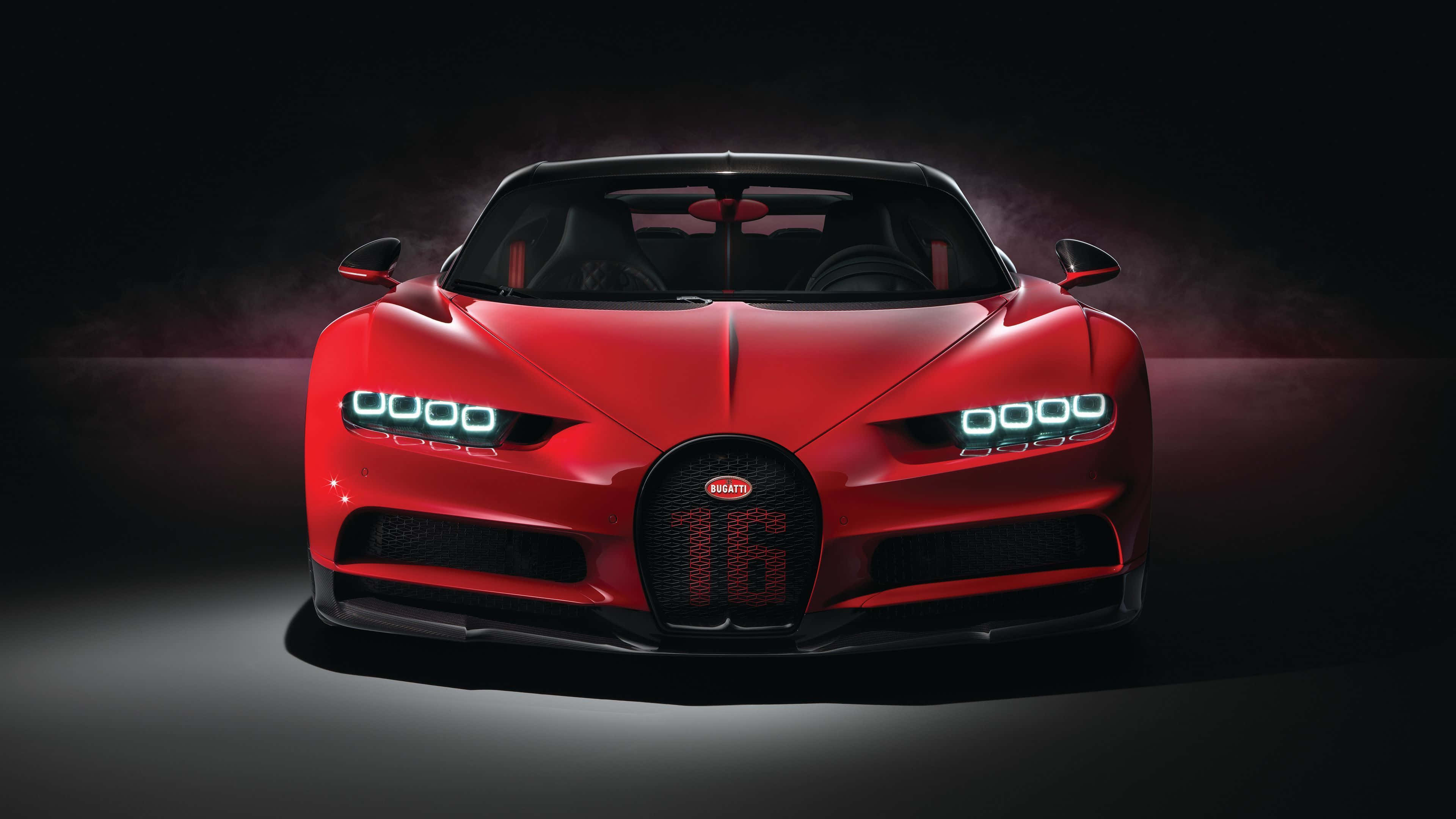 Best Bugatti 桌布 壁紙 — 一輛引人注目的紅色Bugatti Chiron Super Sport 300+在戲劇性的工作室燈光下閃耀，車頭燈發光，背景黑暗煙霧繚繞。
