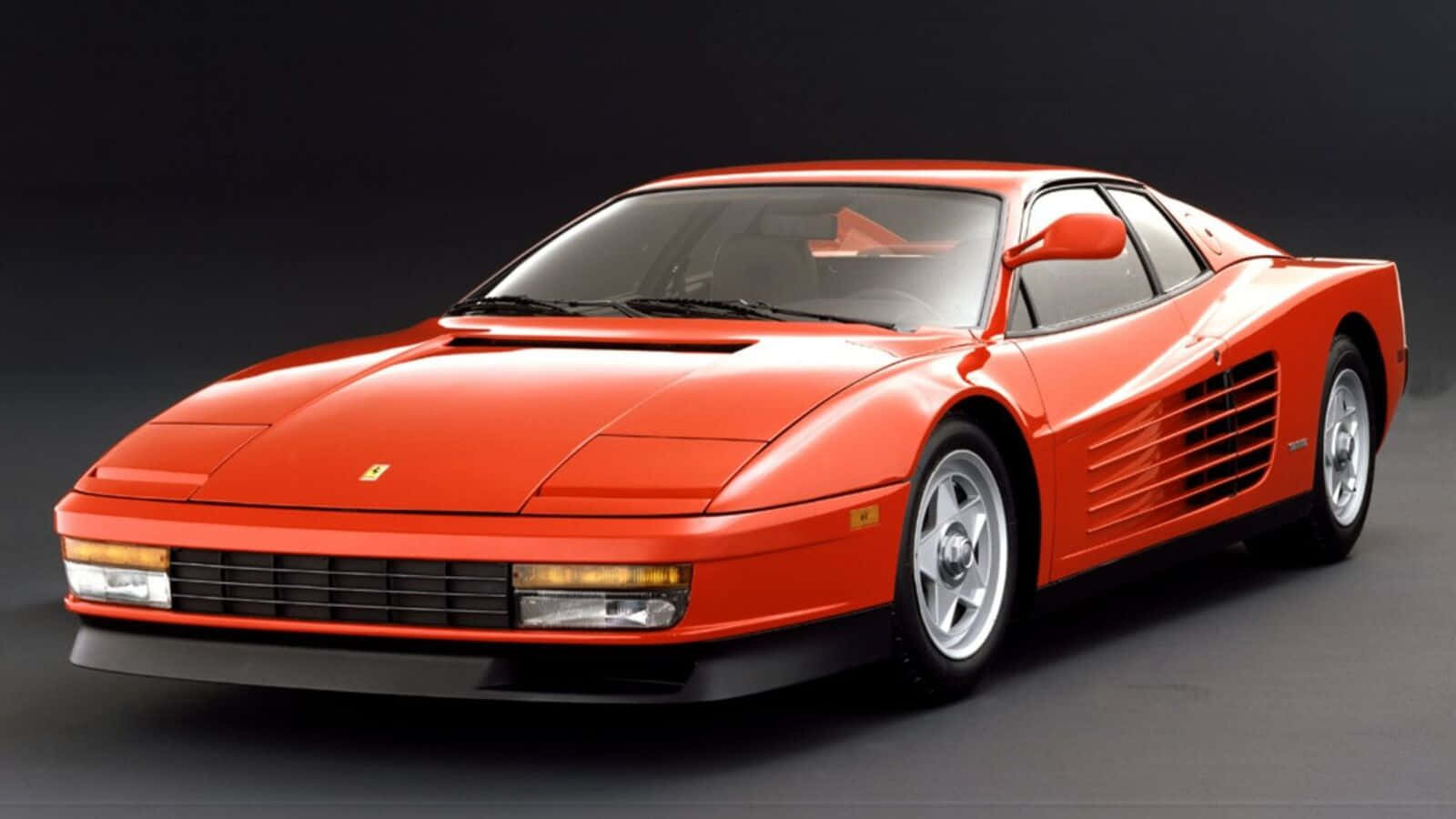 Ferrari Testarossa 桌布 壁紙 — 一輛引人注目的紅色法拉利 Testarossa 在攝影棚燈光下，在深色漸變背景上閃閃發光。