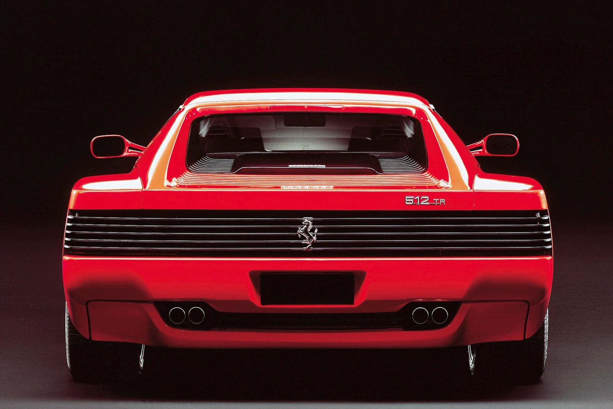 Ferrari Testarossa 桌布 壁紙 — 一輛引人注目的紅色法拉利512 TR，在黑暗的攝影棚背景中從後方觀看，帶有戲劇性的燈光。
