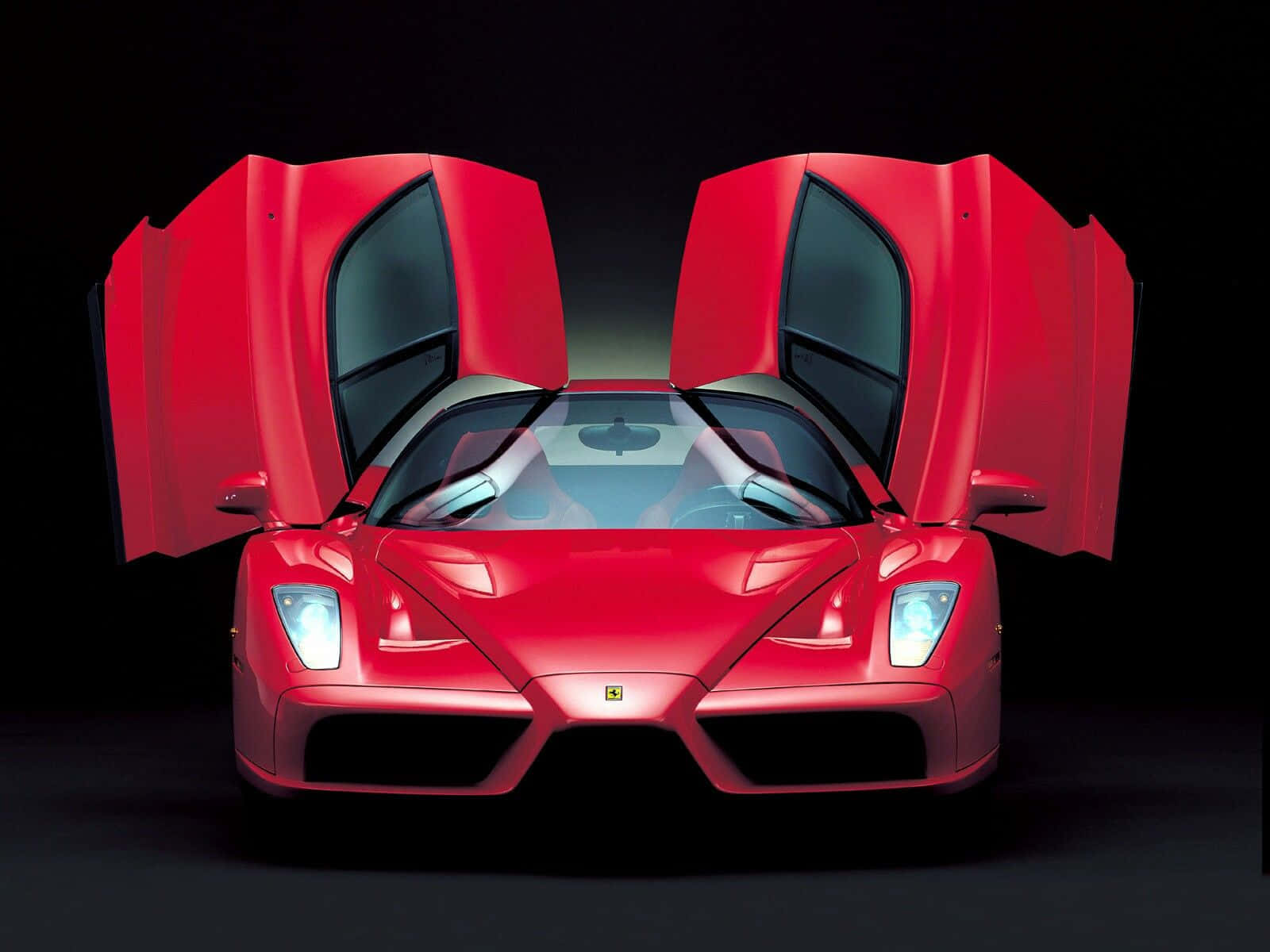 Ferrari Enzo 桌布 壁紙 — 一輛引人注目的紅色法拉利Enzo，鷗翼門打開，黑色背景，車頭燈發光。