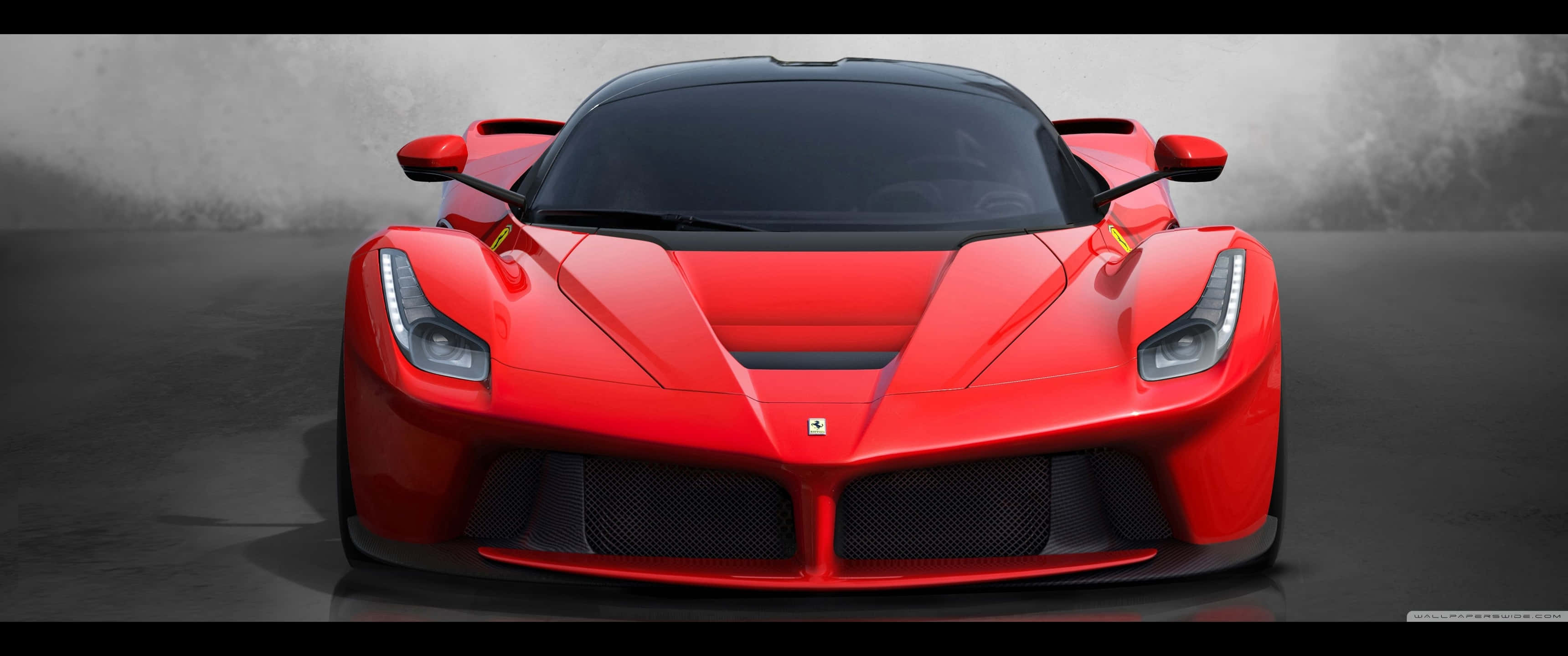 3440x1440p Ferrari 桌布 壁紙 — 一輛引人注目的紅色法拉利LaFerrari在簡約的工作室中正面朝前，搭配戲劇性的燈光和灰色煙霧背景。