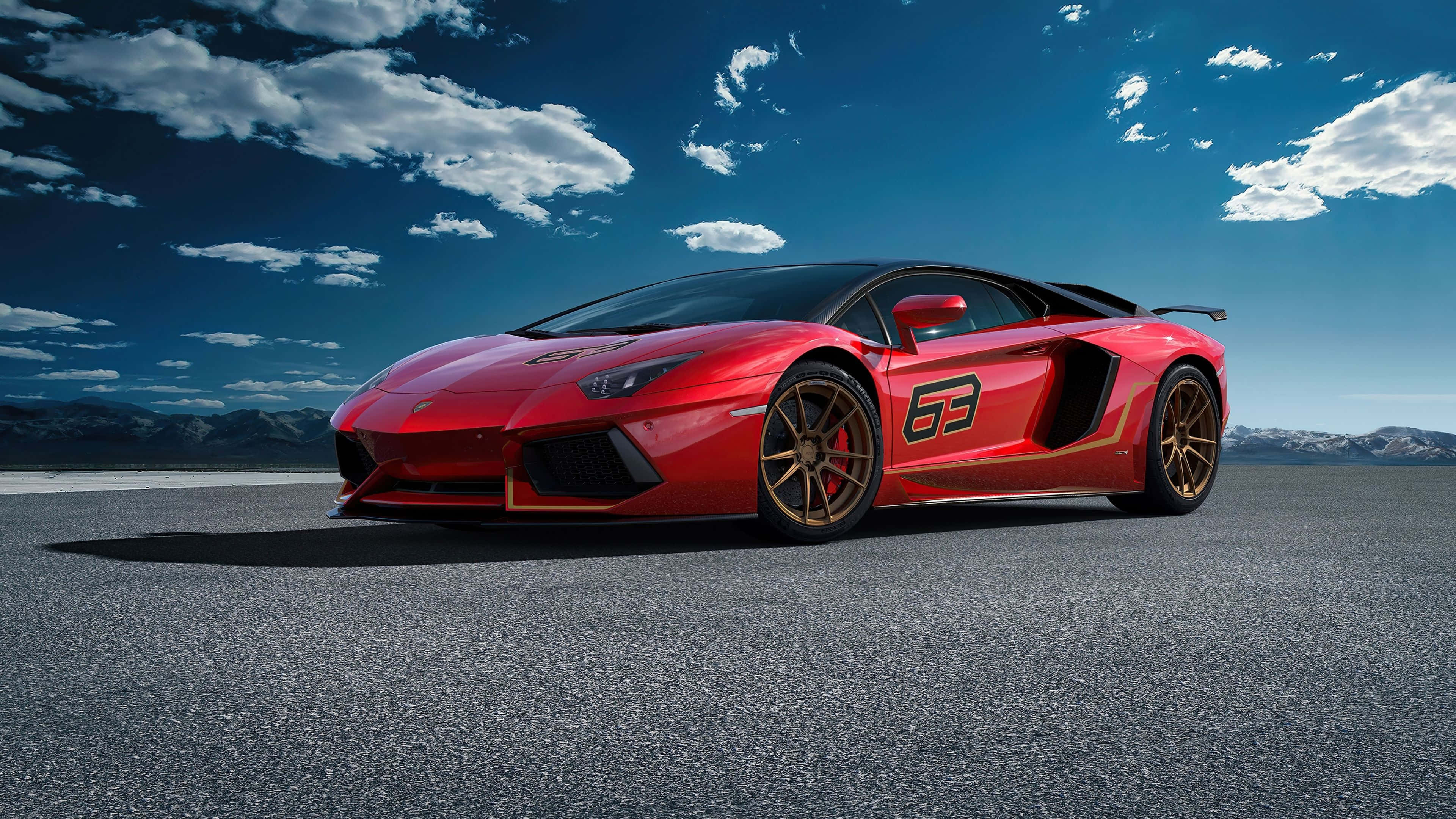 4K 藍寶堅尼 桌布 壁紙 — 一輛引人注目的紅色藍寶堅尼 Aventador SVJ，帶有金色飾邊和賽車號碼「63」，停在沙漠柏油路上，背景是戲劇性的藍天和散落的雲朵。