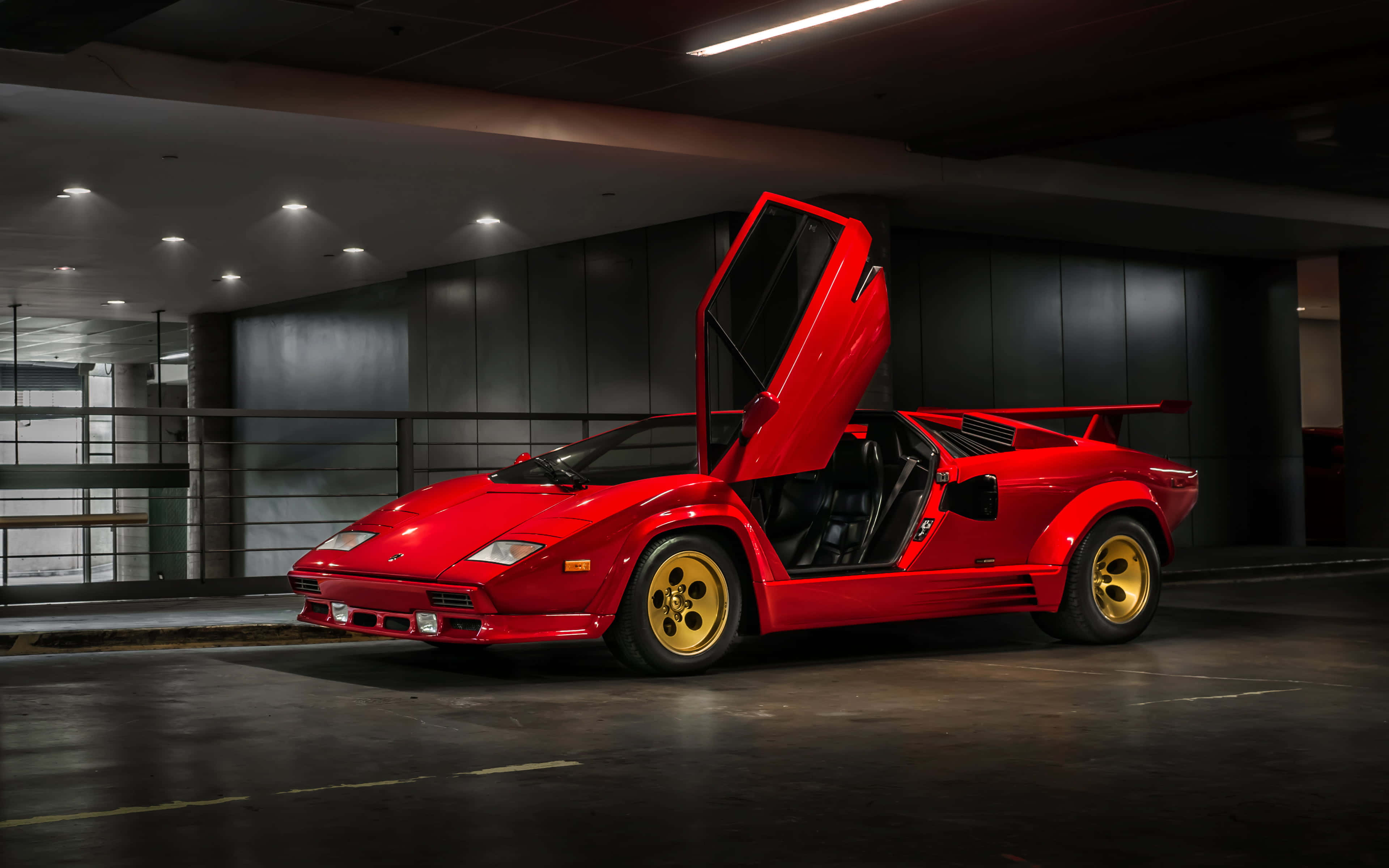 跑車 桌布 壁紙 — 一輛引人注目的紅色藍寶堅尼Countach，鷗翼車門打開，停放在燈光昏暗的現代車庫中。