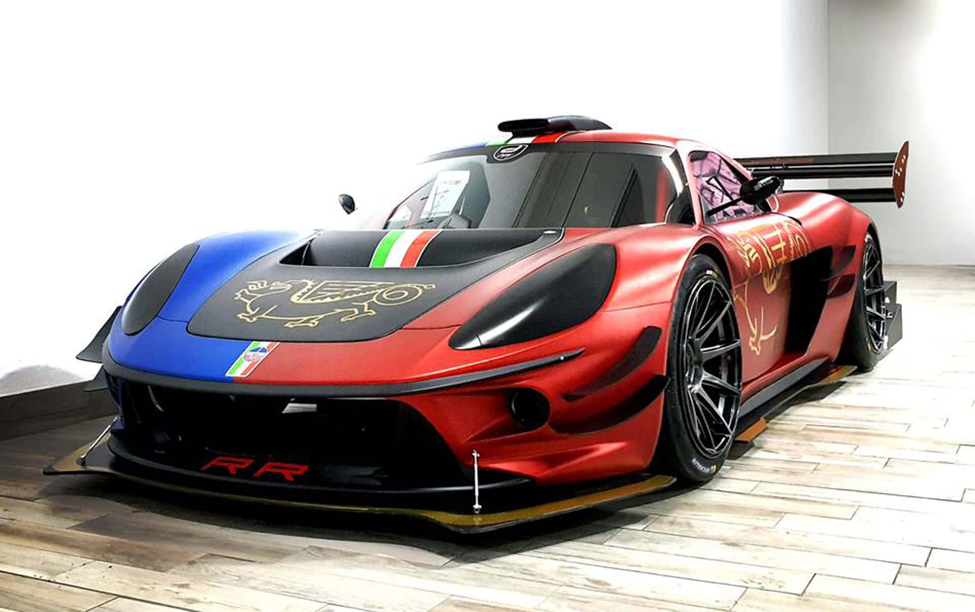 Car Racing 桌布 壁紙 — 一輛引人注目的紅藍色法拉利賽車，帶有金色龍形貼花和義大利國旗條紋，停放在極簡主義工作室的木地板上。